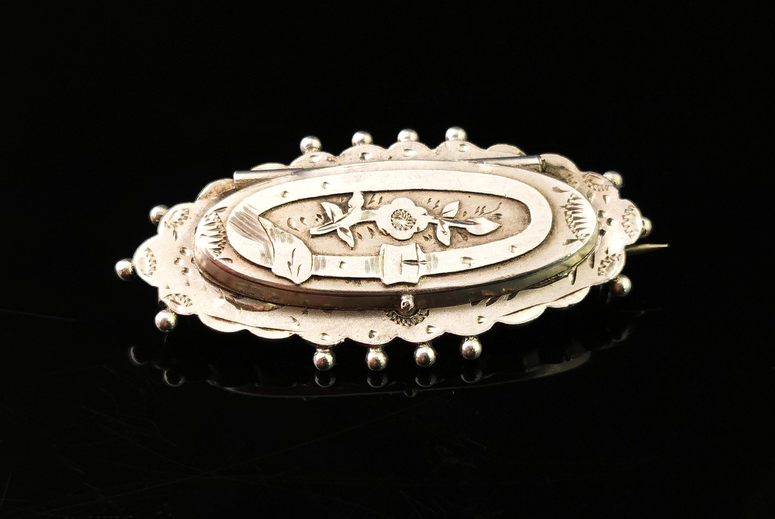 A fine and rare antique silver locket brooch.

This fantastic piece is engraved in the aesthetic manner with foliage and a belt and buckle, the belt / buckle symbolises holding one close.

The top of the brooch opens up revealing a little concealed