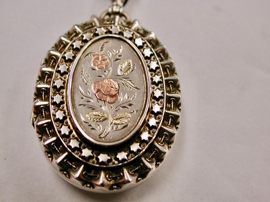 Medaglione d'argento antico con lavorazione in oro bicolore applicata su catena d'argento antico
Questo raffinato medaglione d'argento è stato realizzato nel 1883 a Birmingham dagli Hardy Brothers. 
La catena d'argento è datata circa 1880 e si