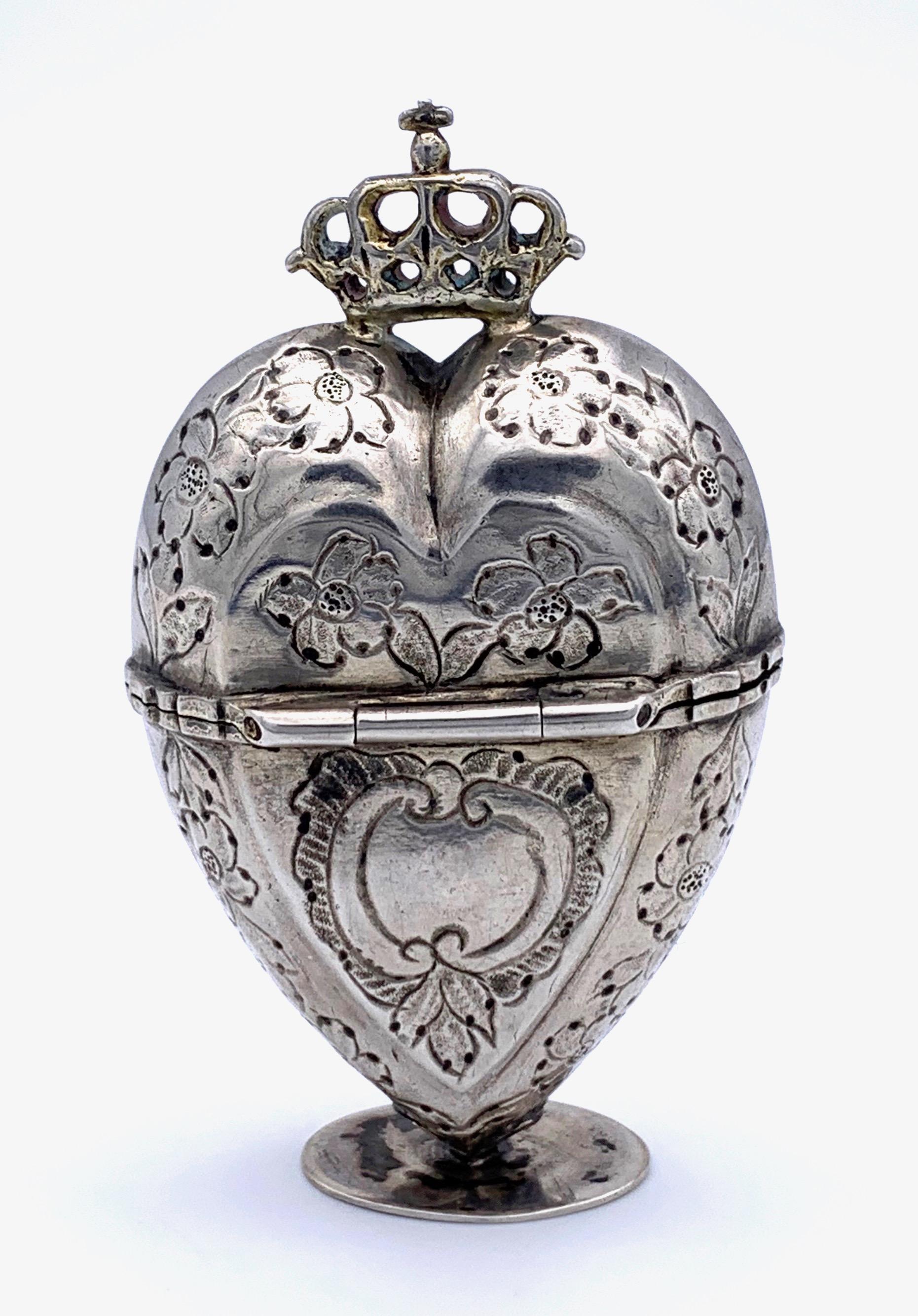 Charming silver box in the shape of a  heart with a crown. The heart is on all sides decorated with engraved flowers. The inside of the box is guilded.