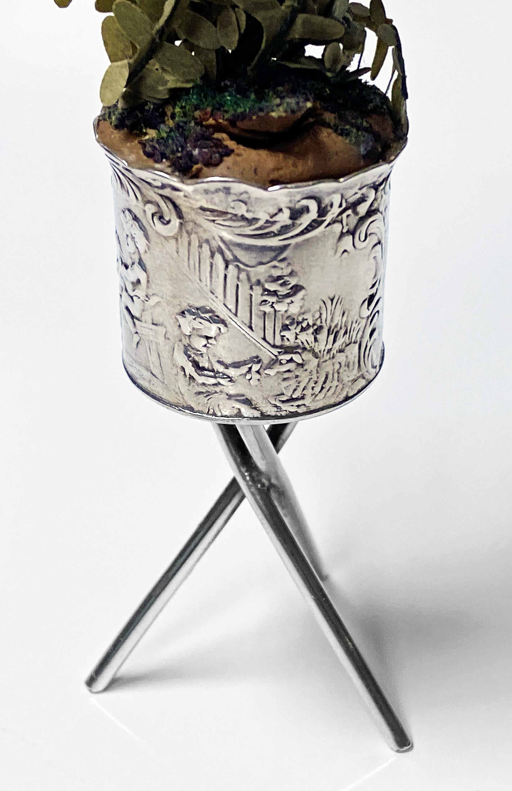 Antique silver miniature planter and stand, Germany, circa 1900. The planter with surround decoration depicting seated cherubs and figures amidst scenes with foxes, flying birds and dogs all on a crossed support stand. Pseudo German Hanau marks to
