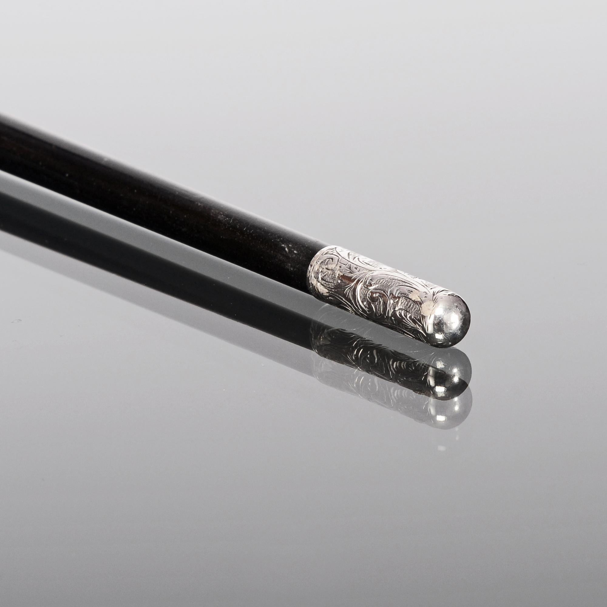 Late-Victorian conductor's baton of ebonised wood and fitted with hand-engraved silver mounts. The octagonal top and middle silver sections are decorated with panels incorporating hand-engraved diamond patterns alternating with sections of scrolling