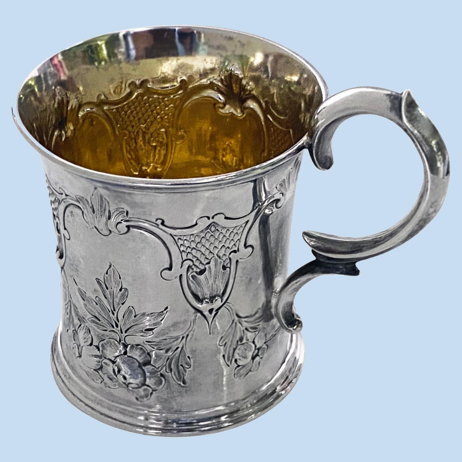 Antique Victorian silver mug, London 1872 Edward Ker Reid. The mug with slight tapering cylindrical body embossed and chased with foliate festoon, gilded interior, double scroll Measures: Height: - 4 inches to top of handle. Weight: 146.62 grams.