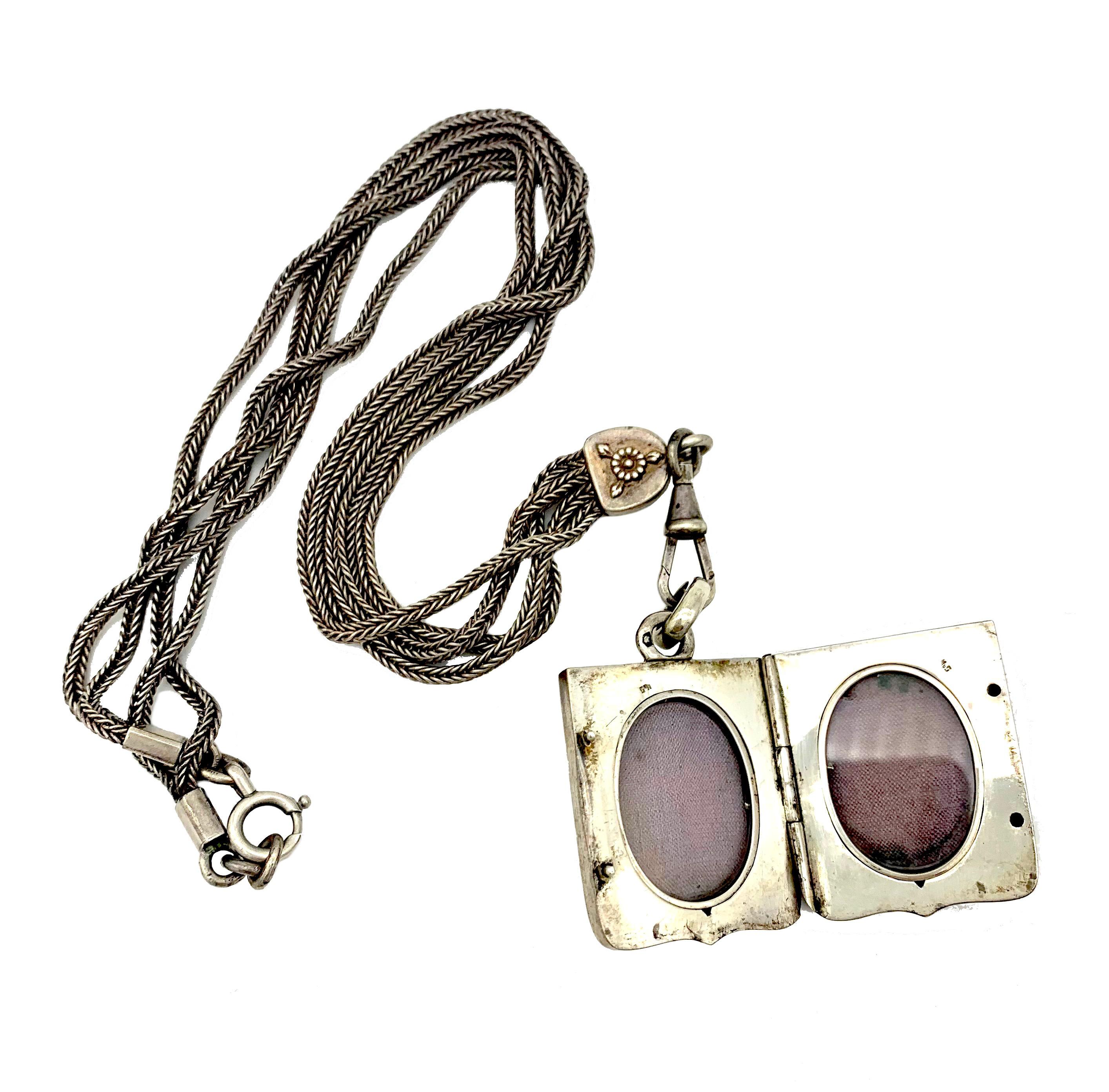 This wonderful silver niello locket is suspended from a double row silver foxtail necklace.  The foxtail chains terminate in a silver element decorated on both sides with a flower in relief.. A swivel suspended from the silver element is holding the