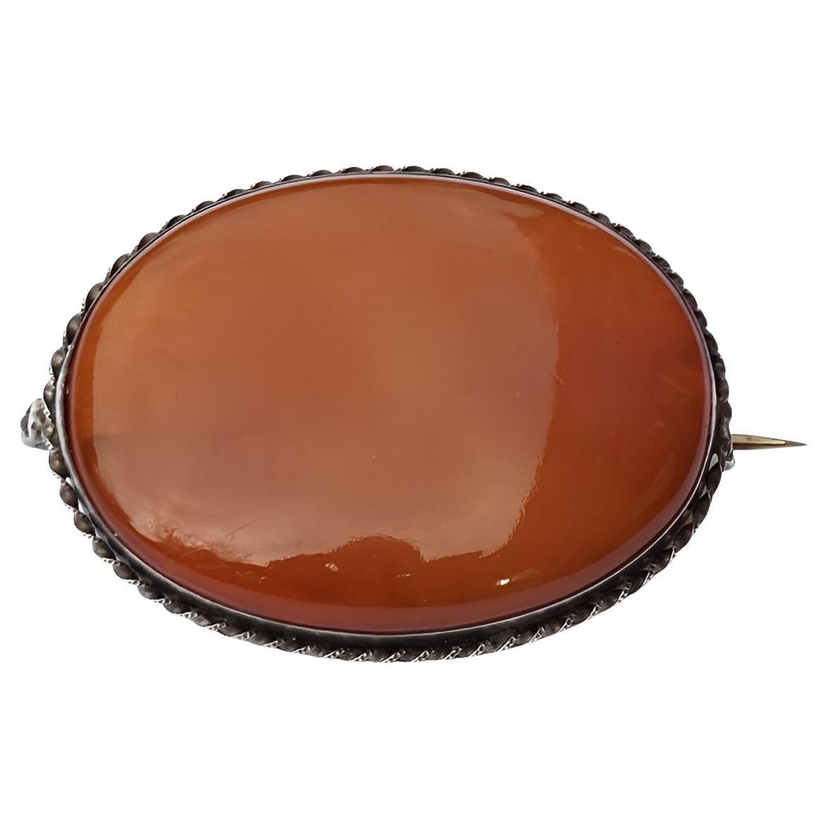 Spilla ovale d
argento antico in corniola lucidata con bordo a spirale