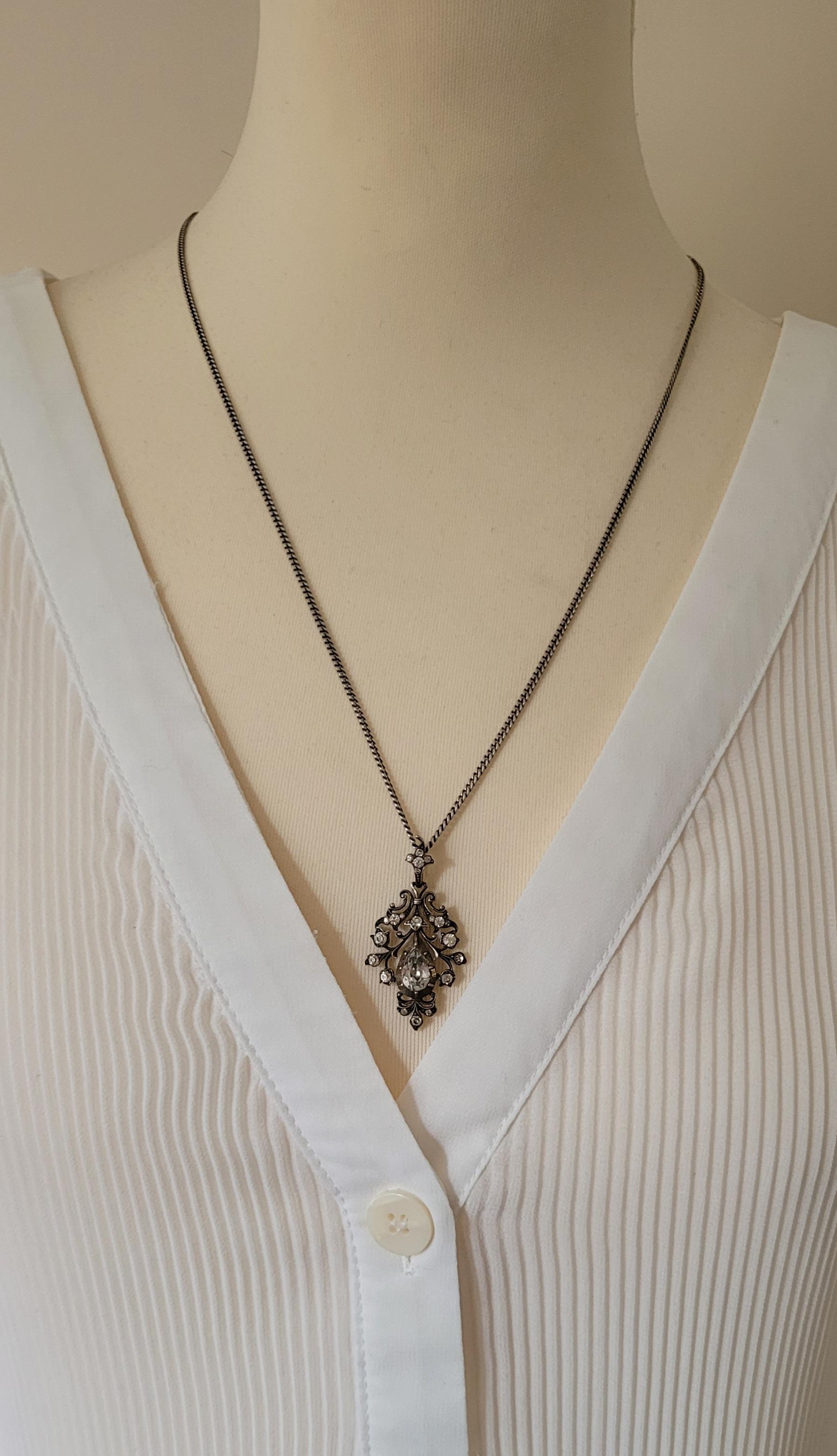 This sterling silver and paste drop pendant is a stunning piece from the late 1800s or early 1900s. Crafted in Georgian style, it comes with a late sterling silver chain and stones in a closed back setting. This piece can be worn either on a chain