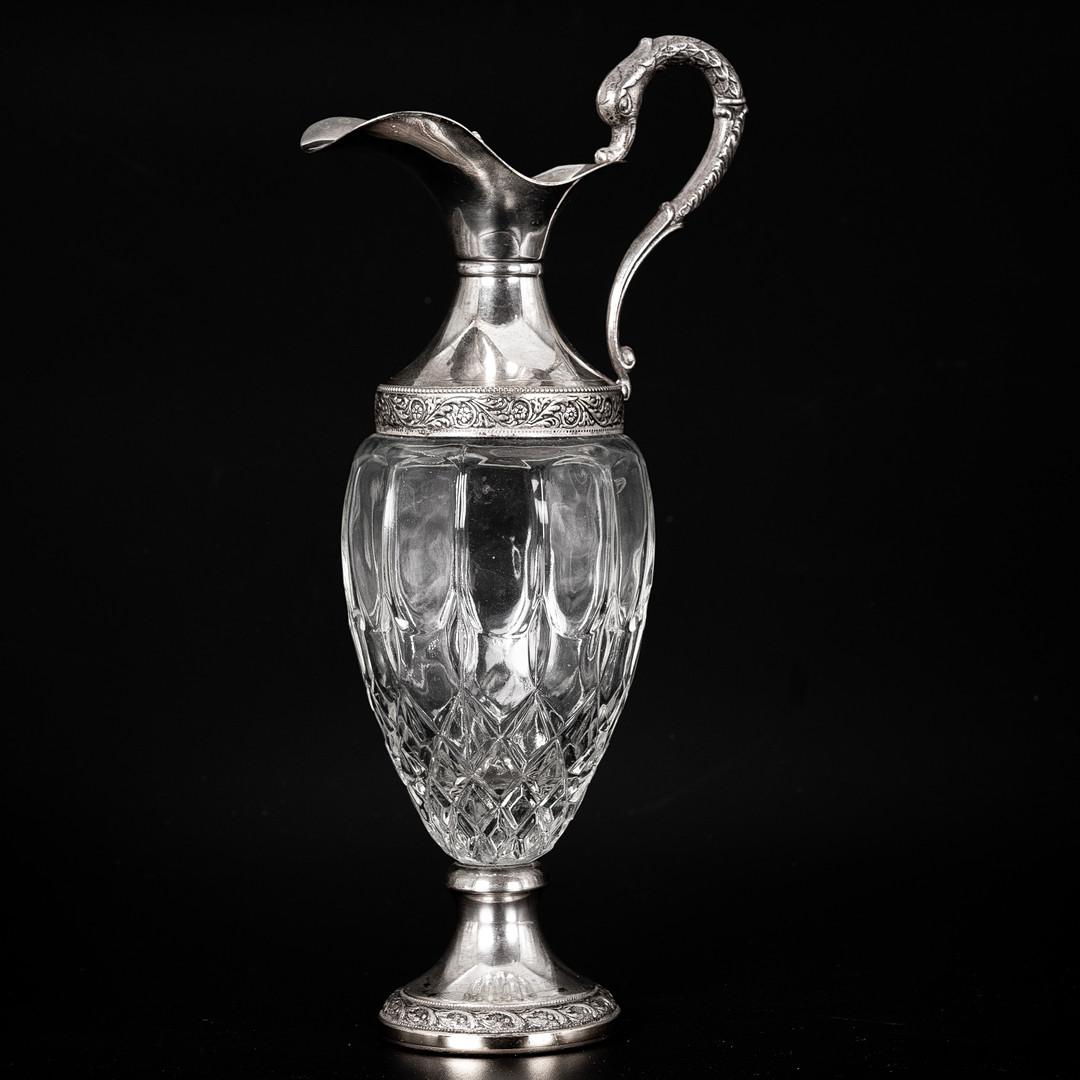 Antigua Jarra Italiana de Plata, JARRA DE CLARET Decorativa de Cristal Cabeza plateada de la década de 1880 con asa de voluta montada y , el cuerpo con decoración de hojas grabadas y una base de cristal tallado en estrella; 30 cm de