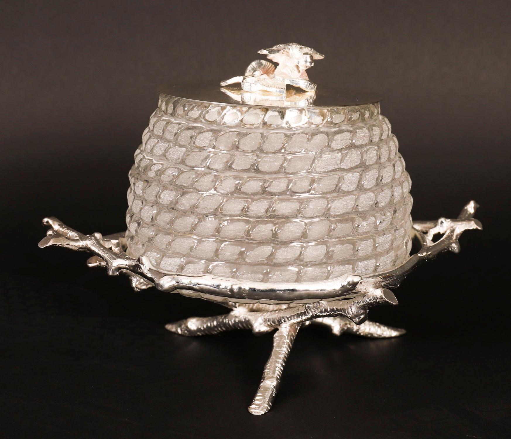 This is gorgeous Antique silver plated and cut glass honey jar on stand, dating from the early 20th Century.

The decorative glass jar is in the shape of a beehive and the silver plated lid is embellished with a bee. The jar rests on a striking