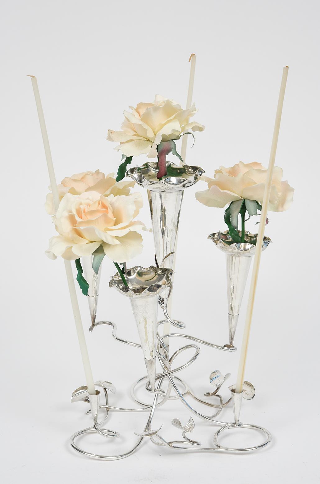This exceptional early 20th century silverplate epergne has elegant detail work on  the 4 tulip inserts which can hold flowers in the central area .  They are scalloped and sit in the intertwined upper level of the base which is garnished with