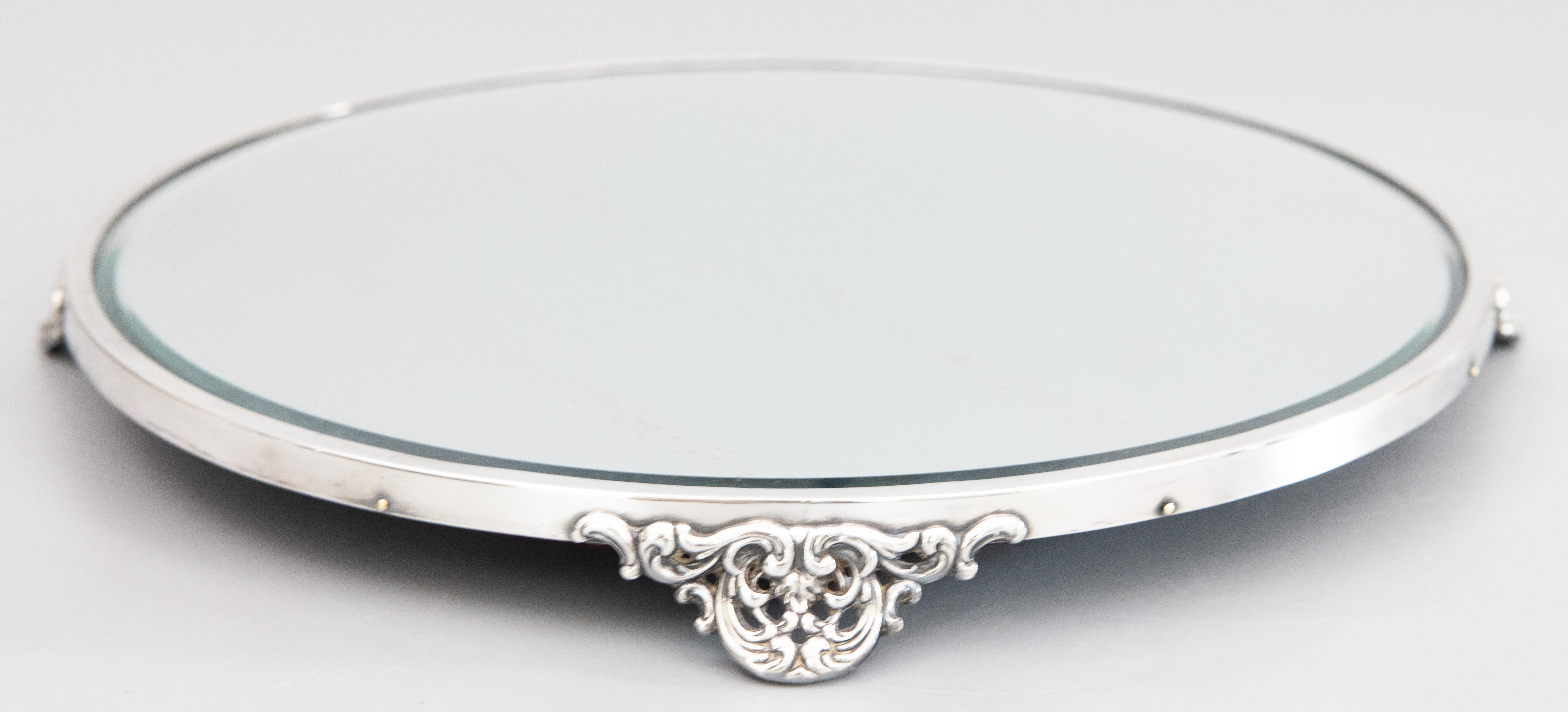 A gorgeous antique silverplate footed mirror plateau, circa 1920. No maker's mark. This beautiful plateau has a lovely silver patina, ornate feet, and an inset 13.75