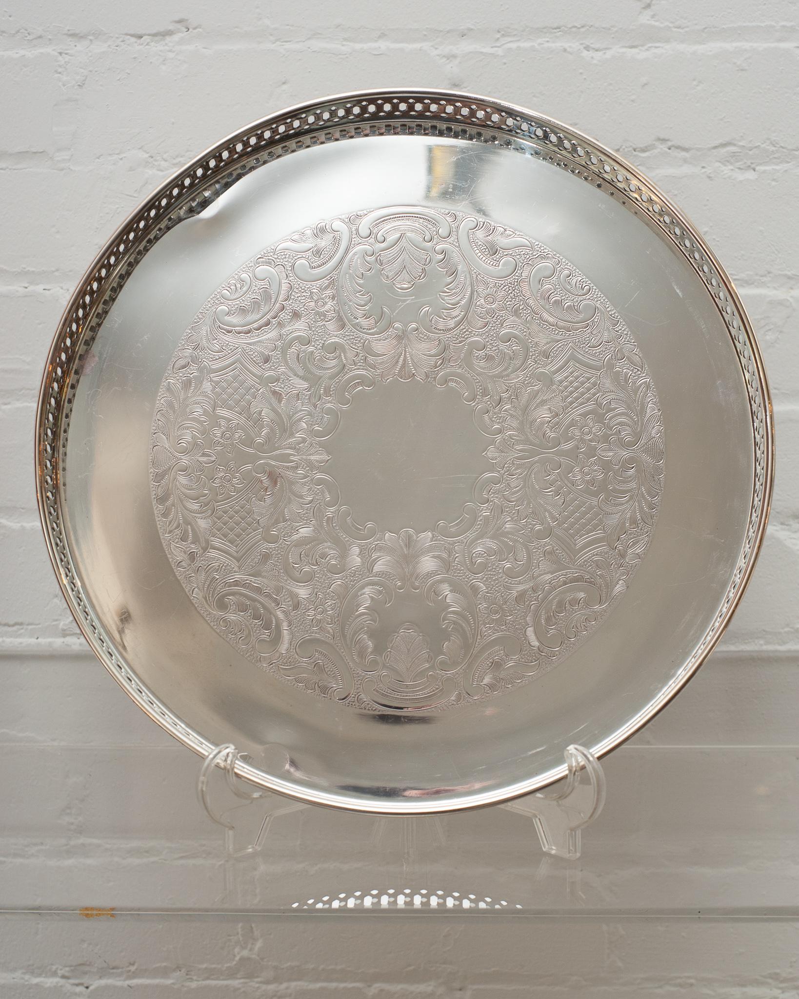 An antique silver plate round serving tray with gallery rim.