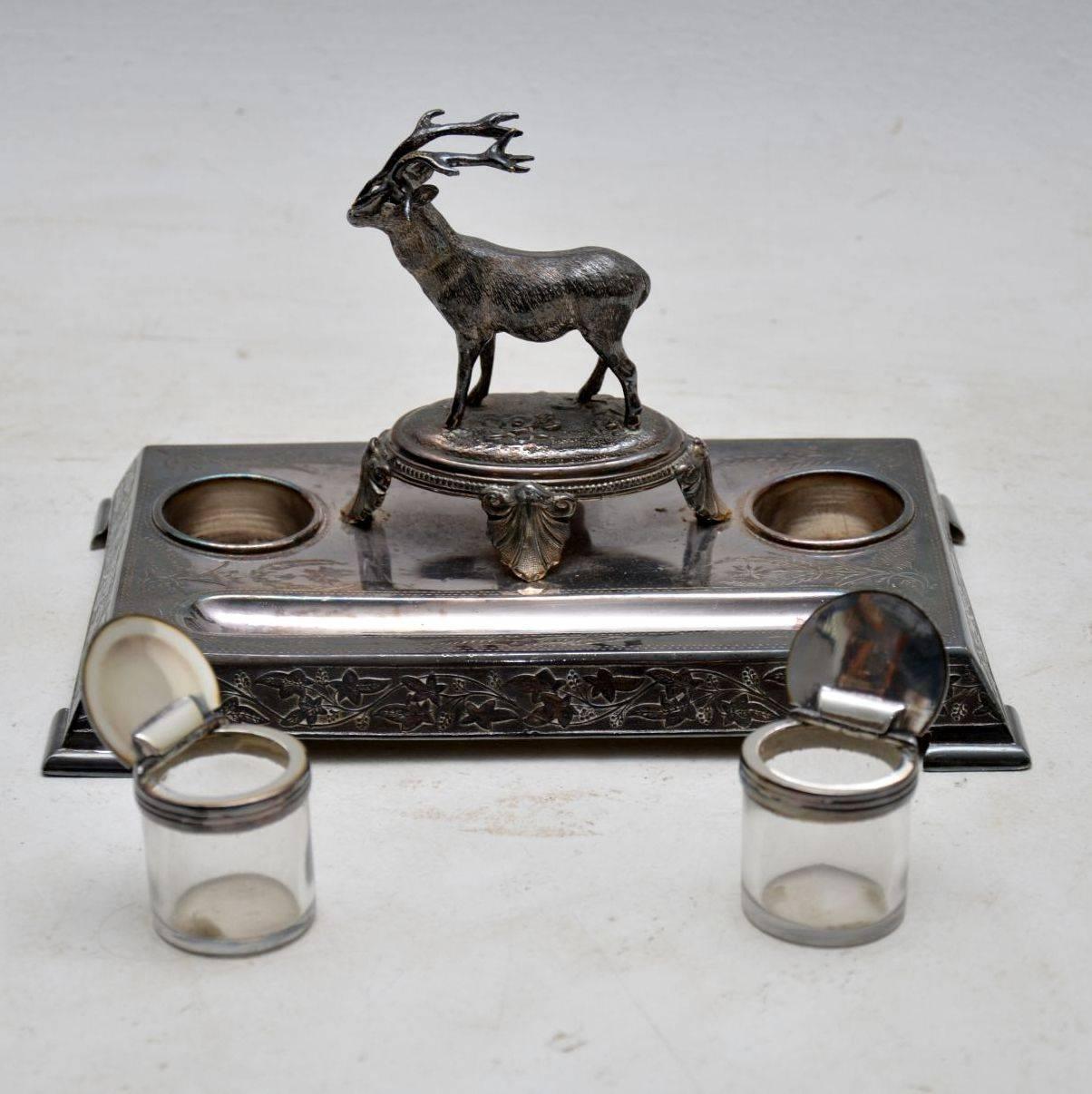 Antique Victorian silver plated inkwell stand with a well defined stag in the centre. It was made by James Deakin and his name is impressed on the underside. The silver plate is very tarnished and needs a good silver polish. Both the glass inkwell