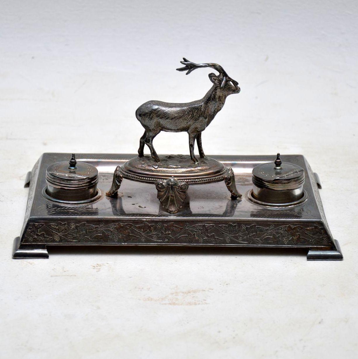 Antique Victorian silver plated inkwell stand with a well defined stag in the centre. It was made by James Deakin & his name is impressed on the underside. The silver plate is very tarnished and needs a good silver polish. Both the glass inkwell are