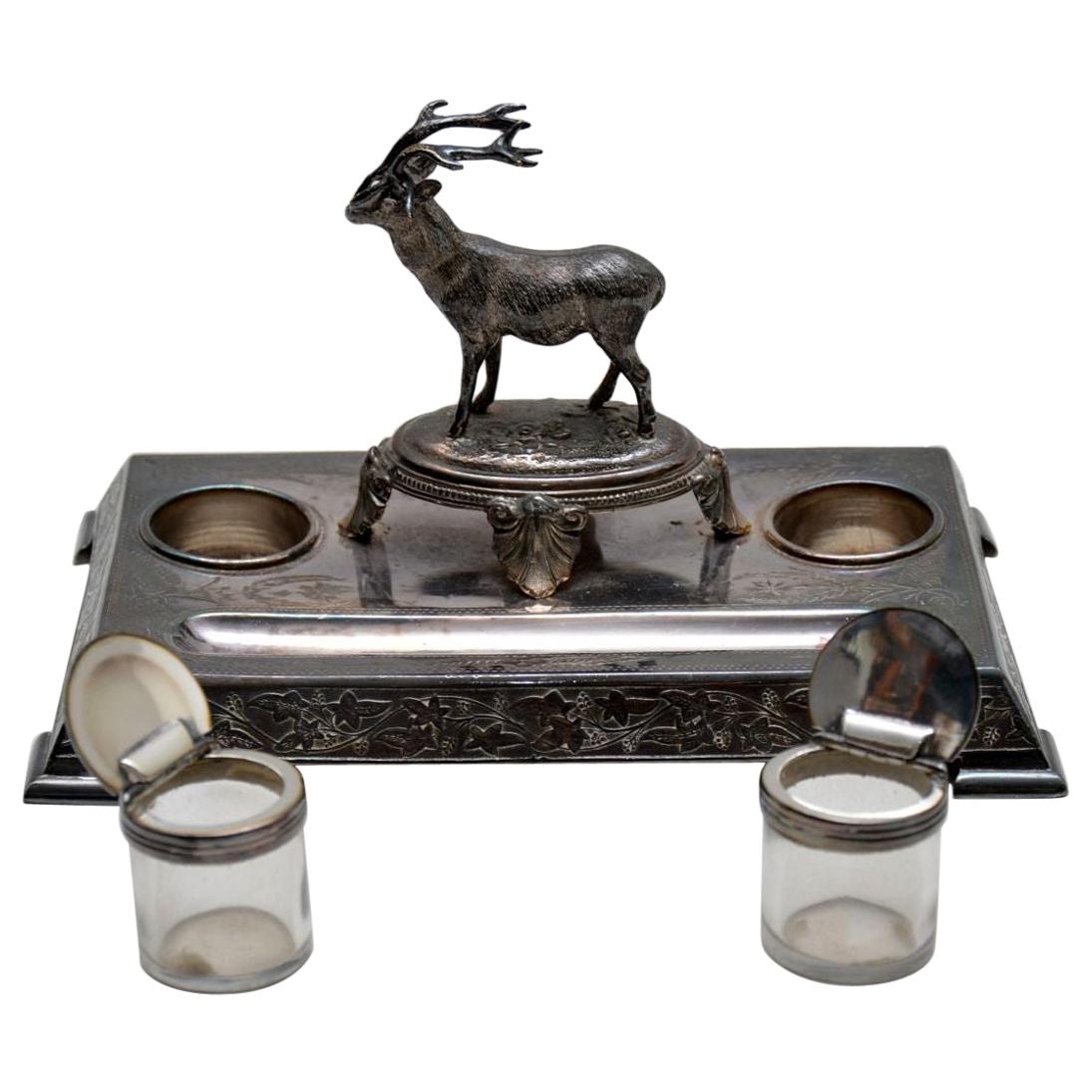 Antique Victorian silver plated inkwell stand with a well defined stag in the centre.

It was made by James Deakin & his name is impressed on the underside.

The silver plate is very tarnished and needs a good silver polish. Both the glass