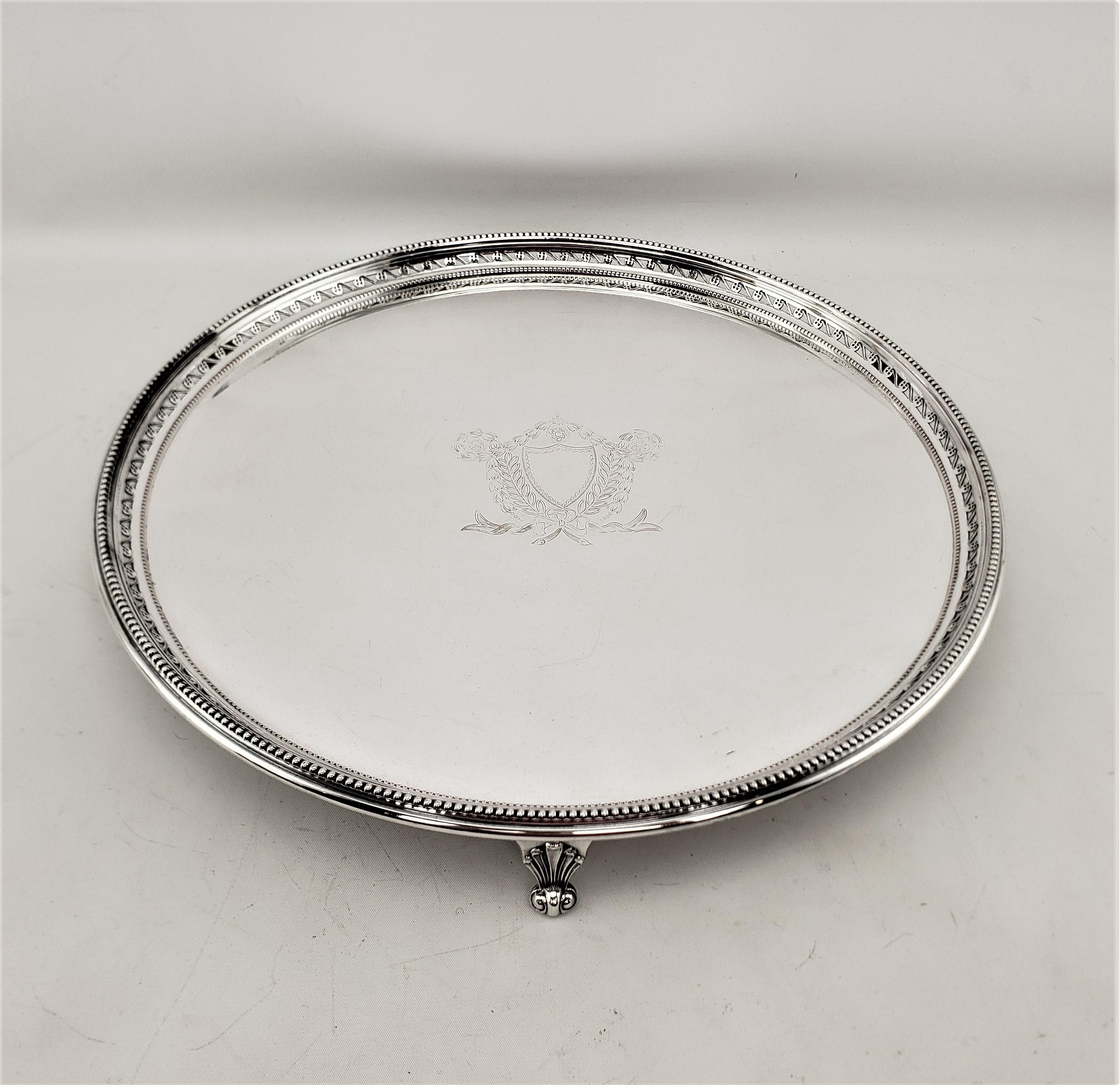 This round silver plated serving tray or salva was made by the renowned Barker Ellis Silver Company of England in approximately 1920 and done in the period Art Deco style. The tray has an engraved shield in the middle, surrounded by stylized leaves