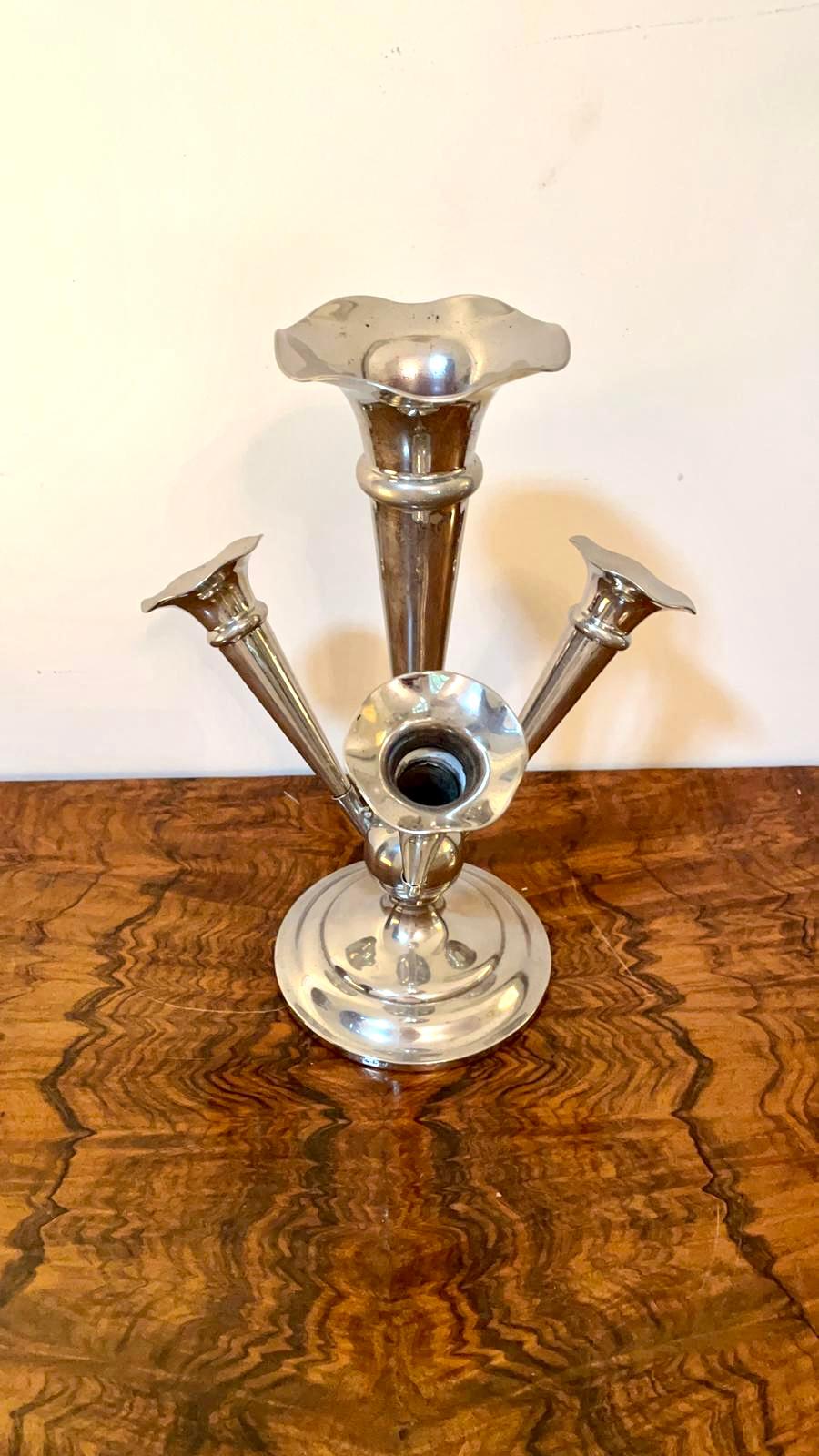 Antique silver plated centrepiece
 
Antique silver plated centrepiece having a large shaped trumpet to the centre with three smaller shaped trumpets in a quality silver plated stand and raised on a shaped round base.

A very attractive example
