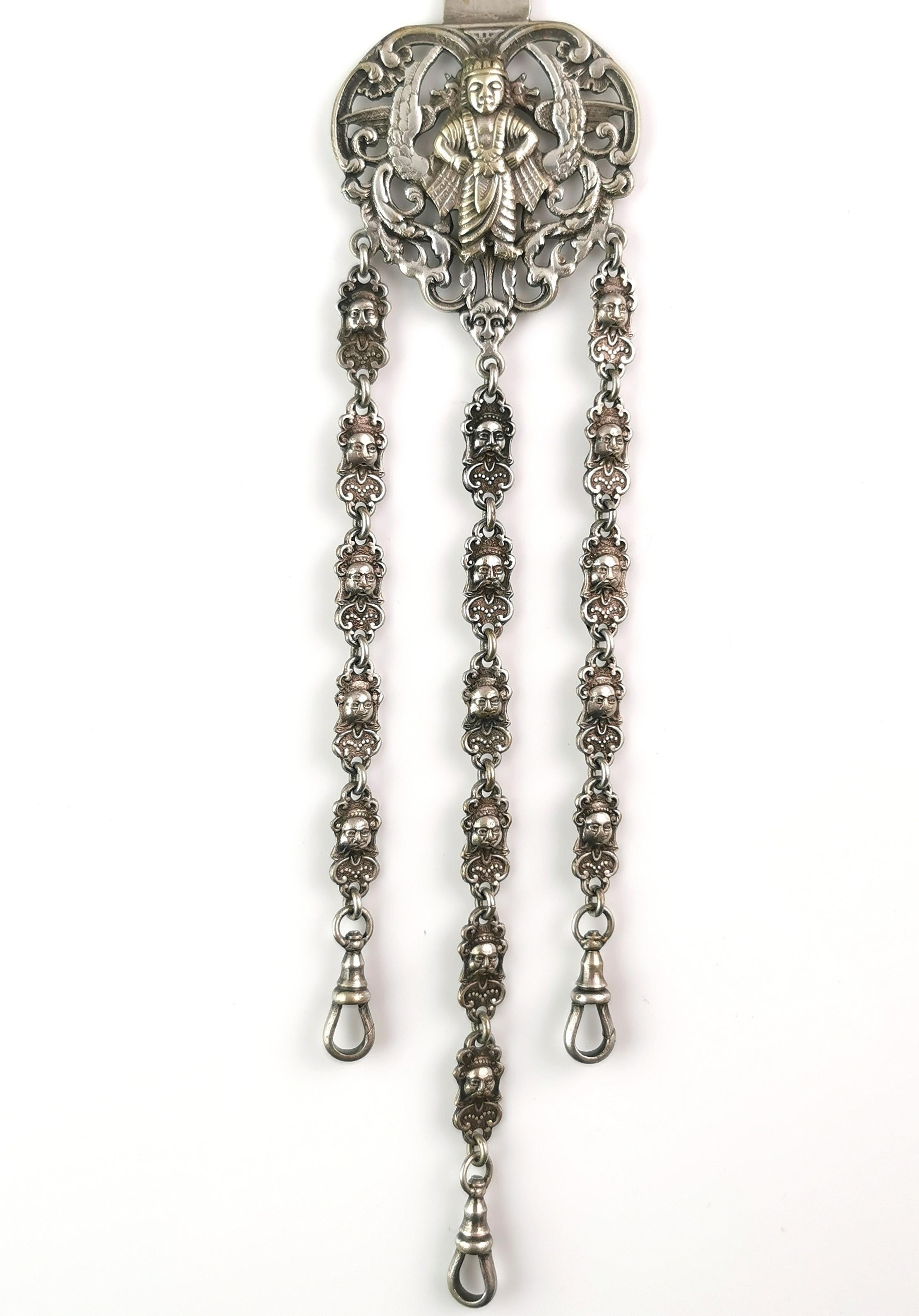 An incredible antique silver plated chatelaine.

A truly beautiful piece, designed to be worn clipped to a belt or sash, the chatelaine has a wonderful design featuring Buddhist Deities and the links are made up of individual mask design lozenges