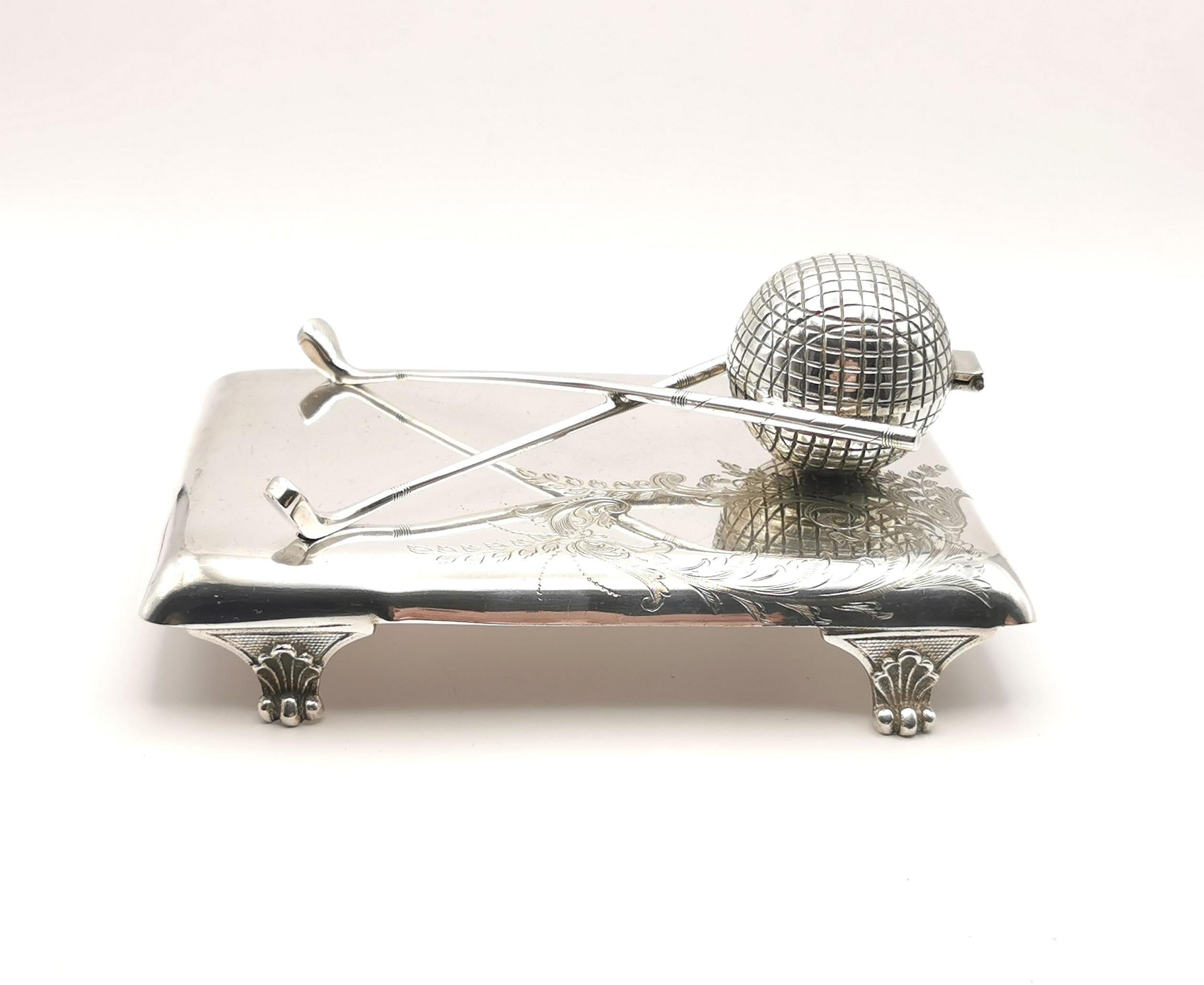 An interesting antique Edwardian era silver plated inkstand.

A heavy and substantial piece, very well made with a golfing theme, there is a pen rest comprised of two crossed golf clubs and the inkwell itself is within the golf ball.

It is a