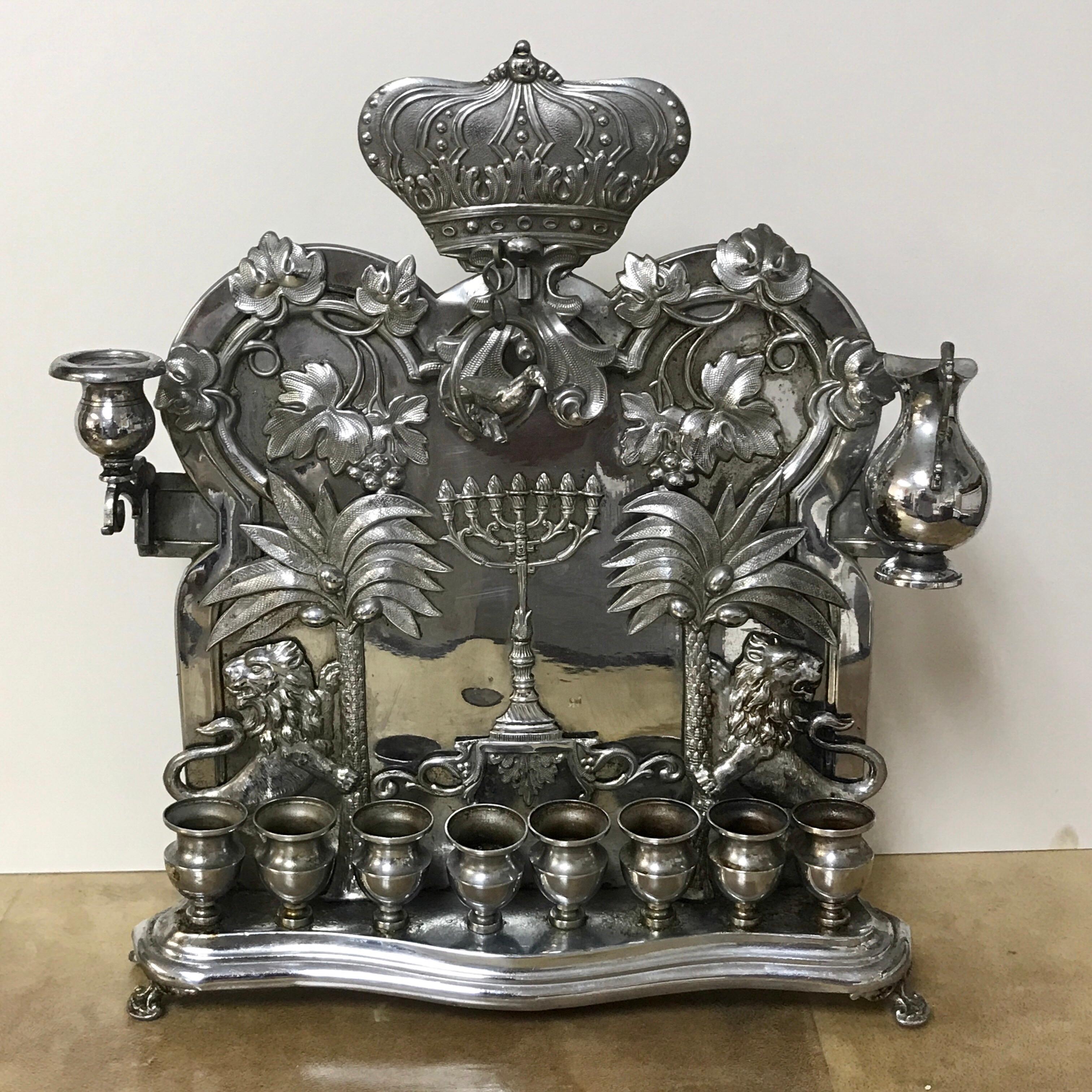 Antique silver plated Hannukah lamp, complete
Hallmarked for B. Henneberg Warszawa, circa 1898
Of typical form with upper swing arm candlestick, a resting dove and removable oil jug
Decorated with centre crown, palm trees, lions, central menorah