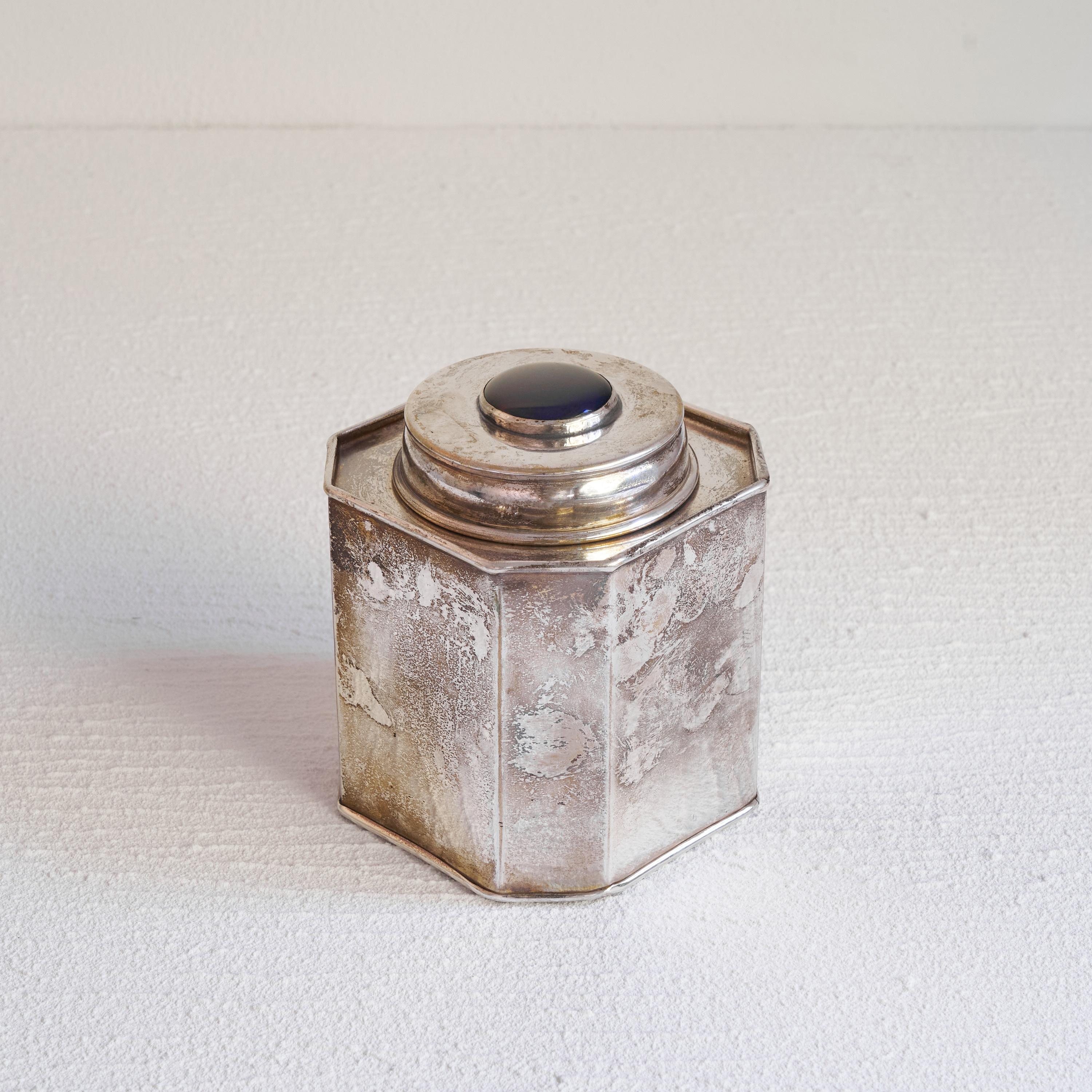 Antique silver plated tea caddy with Lapis Lazuli colored detail. First half of the 20th century. 

Beautiful and wonderfully patinated tea caddy with a striking Lapis Lazuli colored detail in the top. Refined and interesting shaped tea caddy with