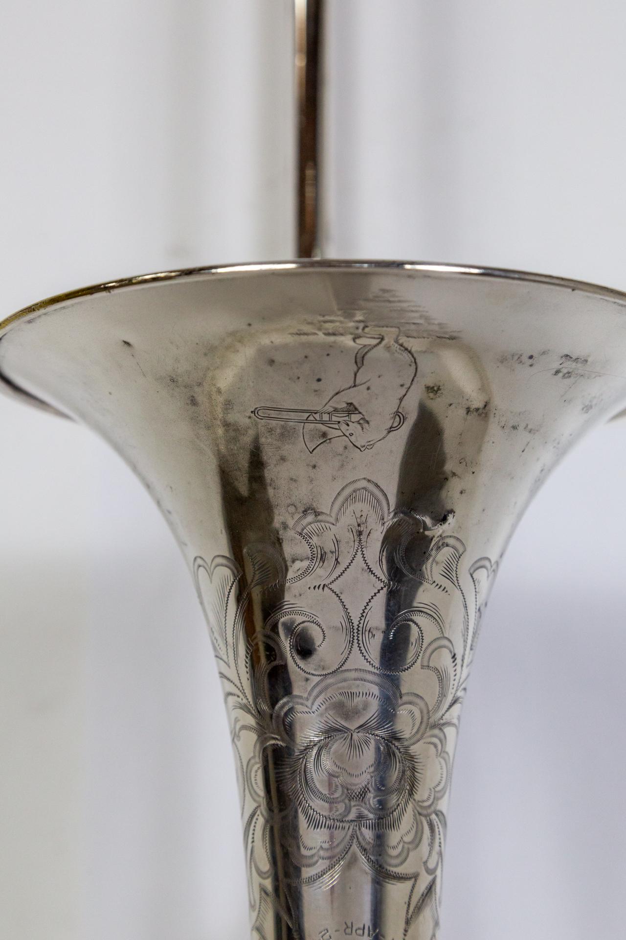 Un oggetto dei primi del Novecento, placcato in argento e inciso, F.E. A. Trombone Olds appena trasformato in un'illuminazione da parete. Si tratta di un up-light con una presa a candelabro nell'apertura del corno. È decorativamente inciso con fiori
