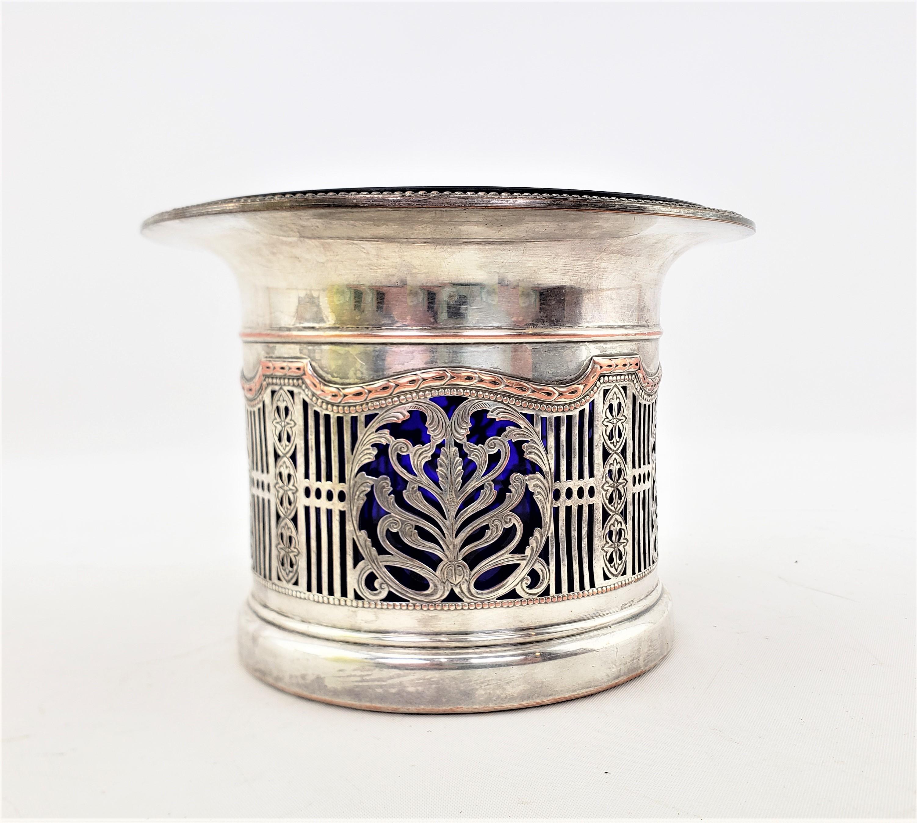 This antique lined bottle coaster is unsigned, but presumed to have originated from England and date to approximately 1890 and done in the period Art Nouveau style. This bottle coaster is composed of silver plate with pierced sides with stylized