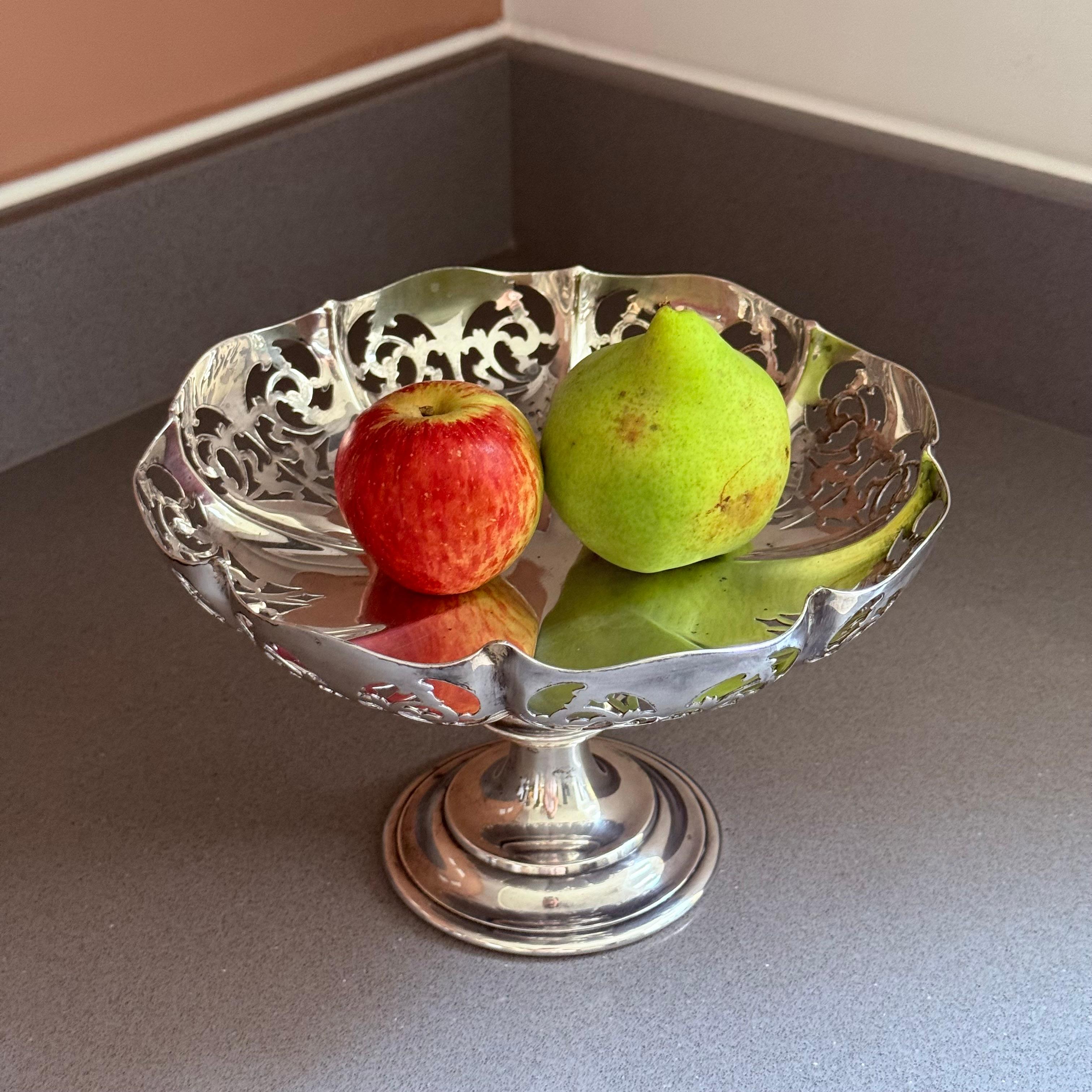 Un cesto di frutta antico placcato in argento di ottima fattura, caratterizzato da un elegante bordo traforato a galleria e da un manico oscillante a corda finemente dettagliato. La forma ovale poggia saldamente su un piede rialzato, offrendo