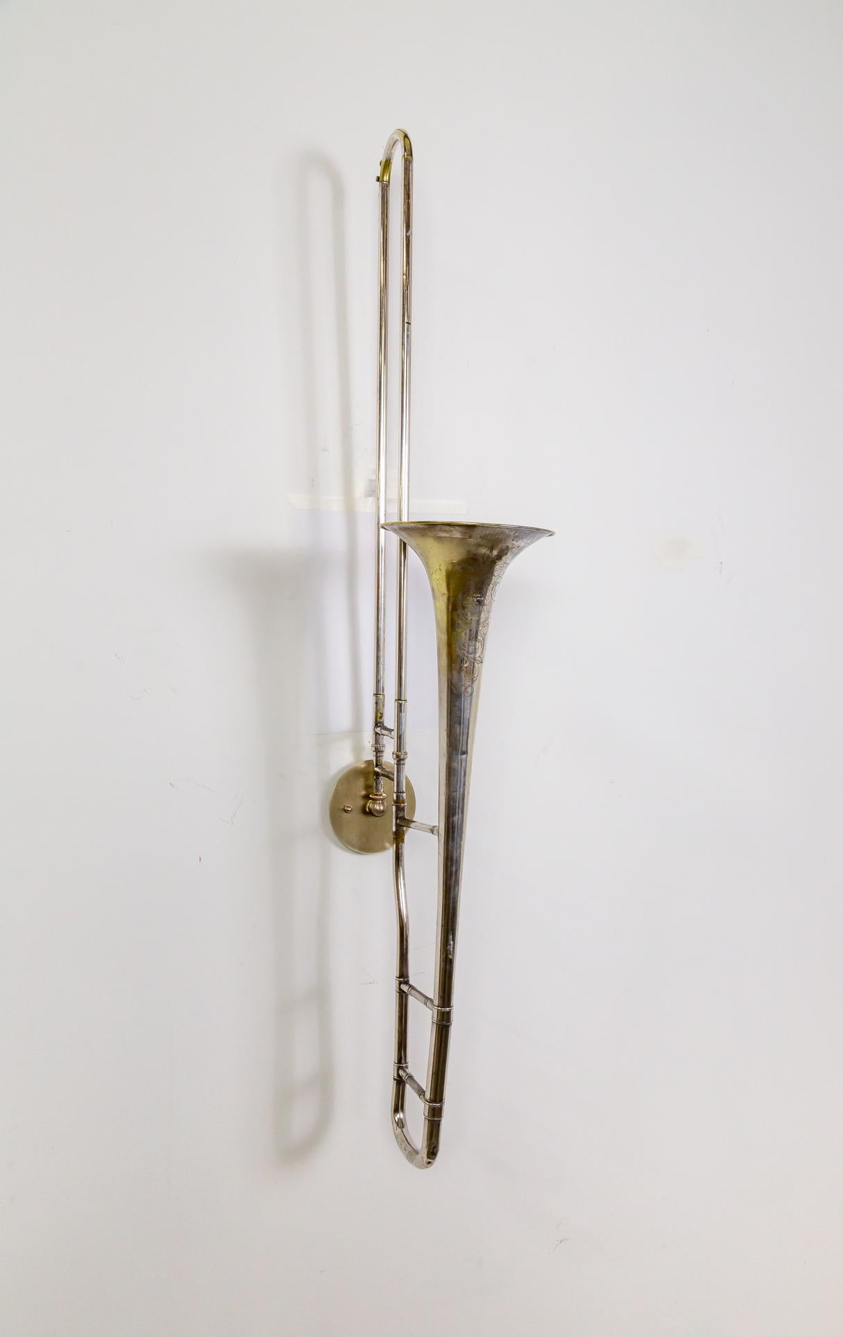 Un trombone York & Sons placcato in argento e inciso dei primi del Novecento, appena trasformato in un'applique. Si tratta di un up-light con una presa a candelabro nell'apertura del corno. È decorativamente inciso con fiori e foglie d'acanto e