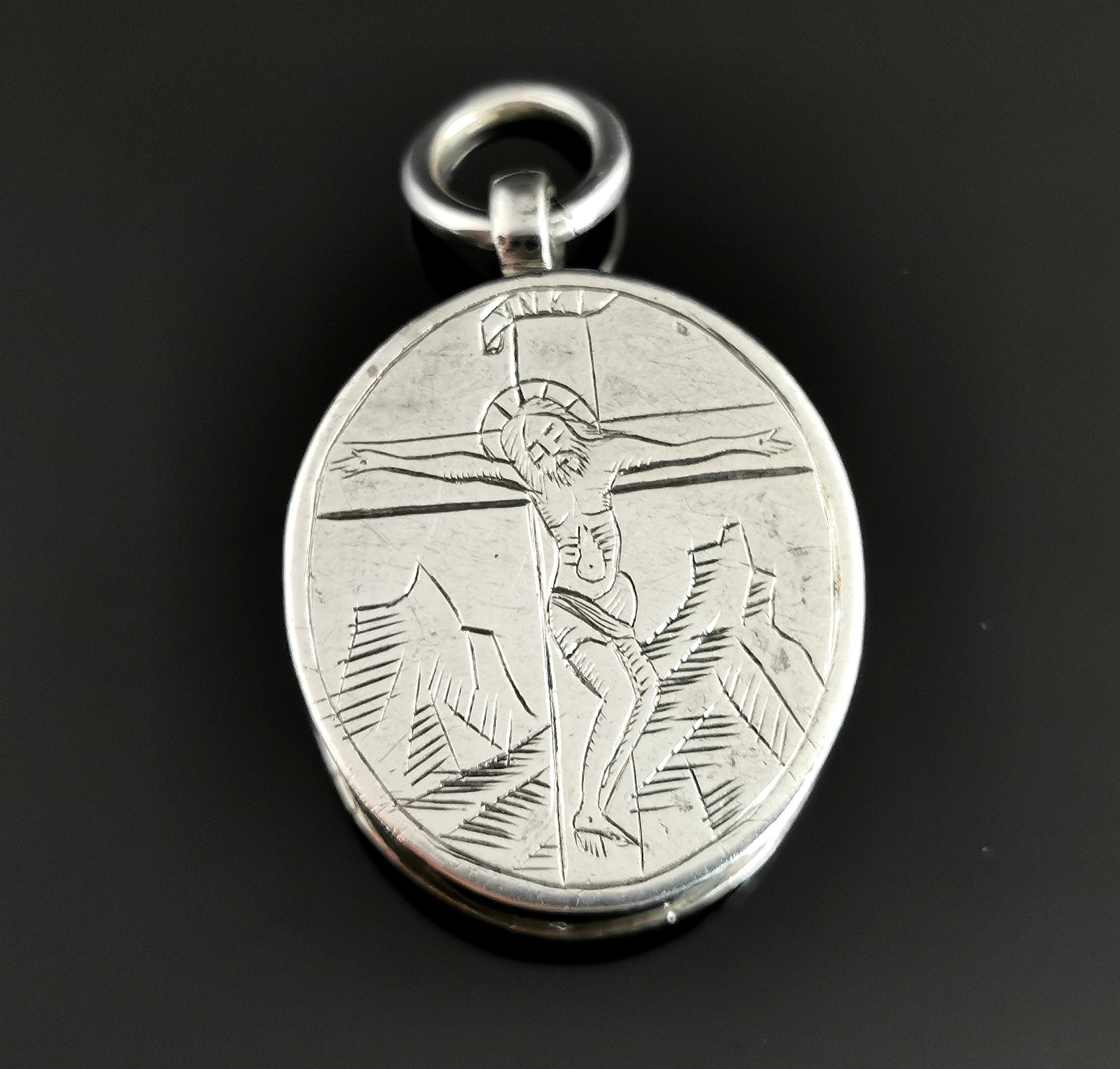 A beautiful and unusual antique silver reliquary locket pendant.

To the front of the locket there is a naively engraved image of Jesus crucified on the cross with the inscription INRI to the top.

The other side has a picture of Mary holding baby