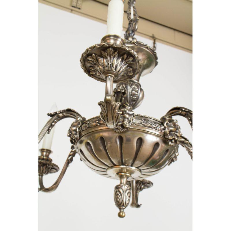 Six light antique silver chandelier. Cast in solid bronze with silver plate and a dark patina. satyr masks at the base of each arm. Late 19th/early 20th century European made. Completely restored and rewired. Carefully adapted for hanging from a