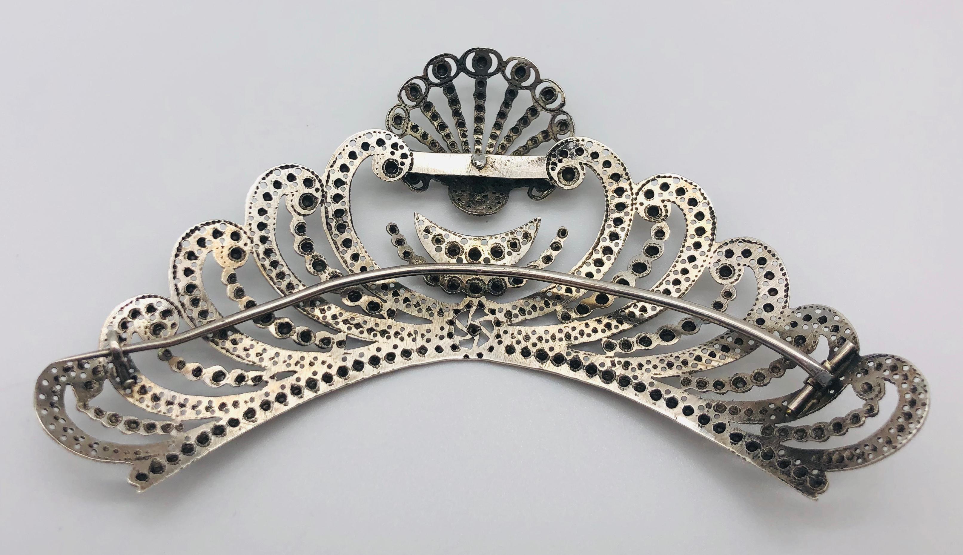 Il diadema per la testa è realizzato in argento e decorato con una smerla, una mezzaluna e una mezza luna. In cima a un grande cuore stilizzato si trova una capasanta. A sinistra e a destra del cuore ci sono otto ornamenti a forma di onda. L'argento