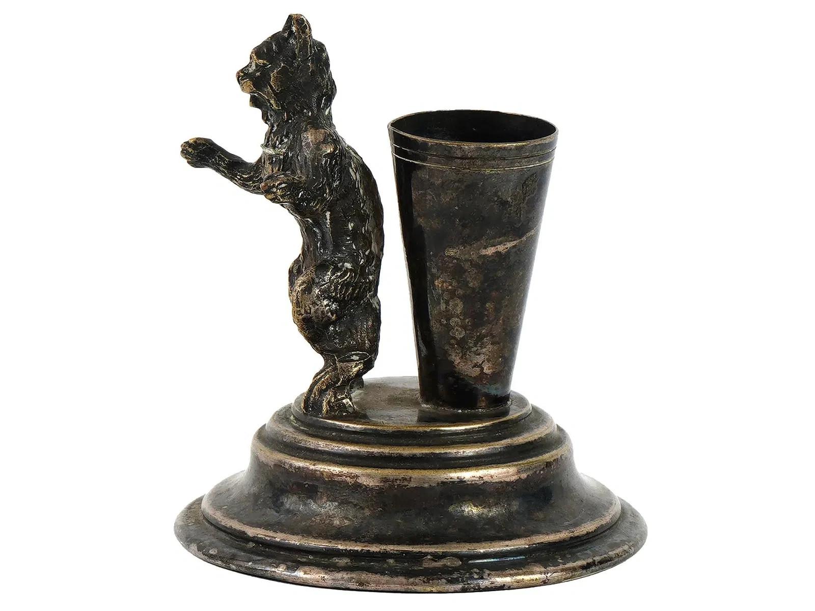 An antique silver toothpick holder with a cat figurine. Circa the late 19th century. The conical toothpick holder sits on a stepped base, with a figurine of a cat standing on its hind legs nearby. Unmarked. Antique European Silverware Collectibles.