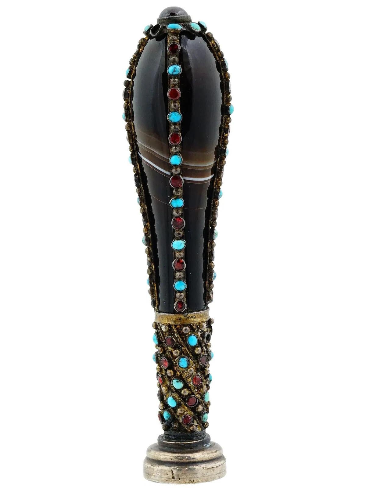 A antique  gilt silver hand seal with black agate body. The piece is richly embellished with turquoise and garnets. The seal part represents a noble court of arms. Unmarked. Total Weight: 105 grams. Collectible Desk Accessories, Writing Instruments,