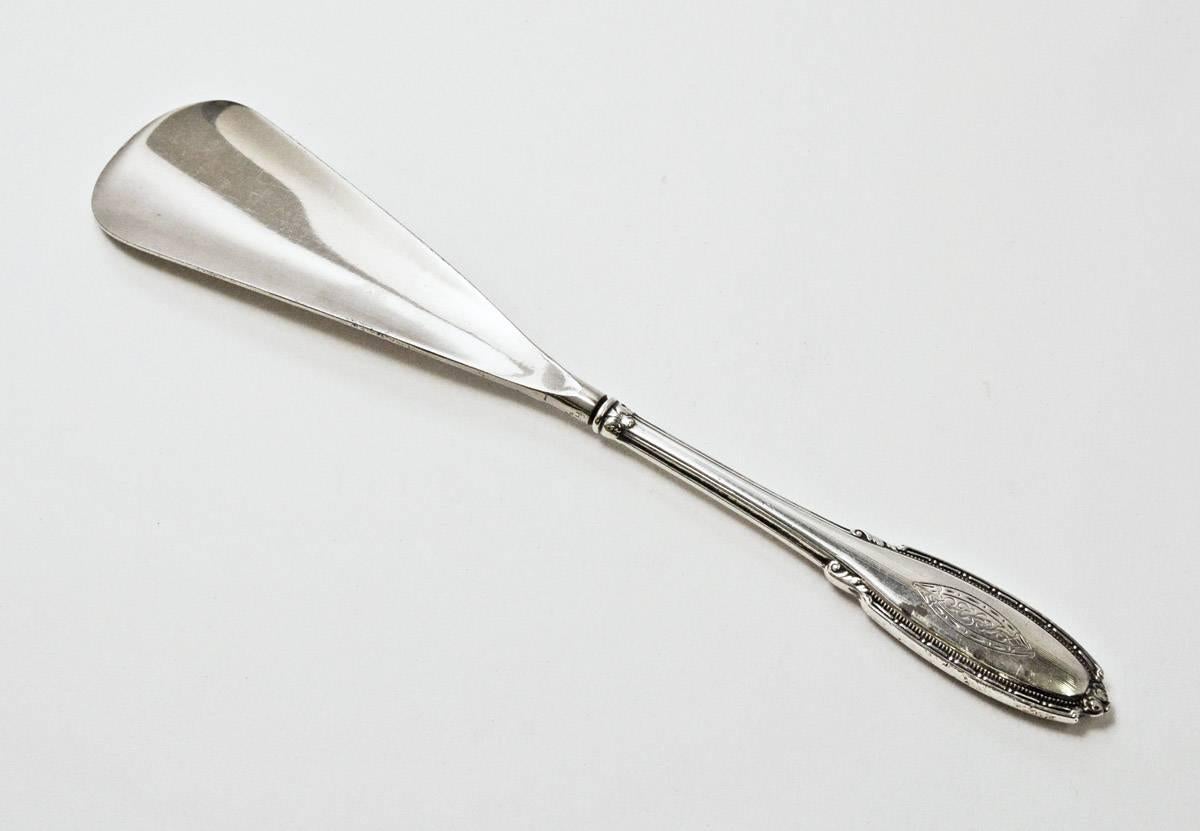 The antique piece has a decorative silver plated handle and a stainless steel shoehorn. Shoe horn portion measures 4 3/4