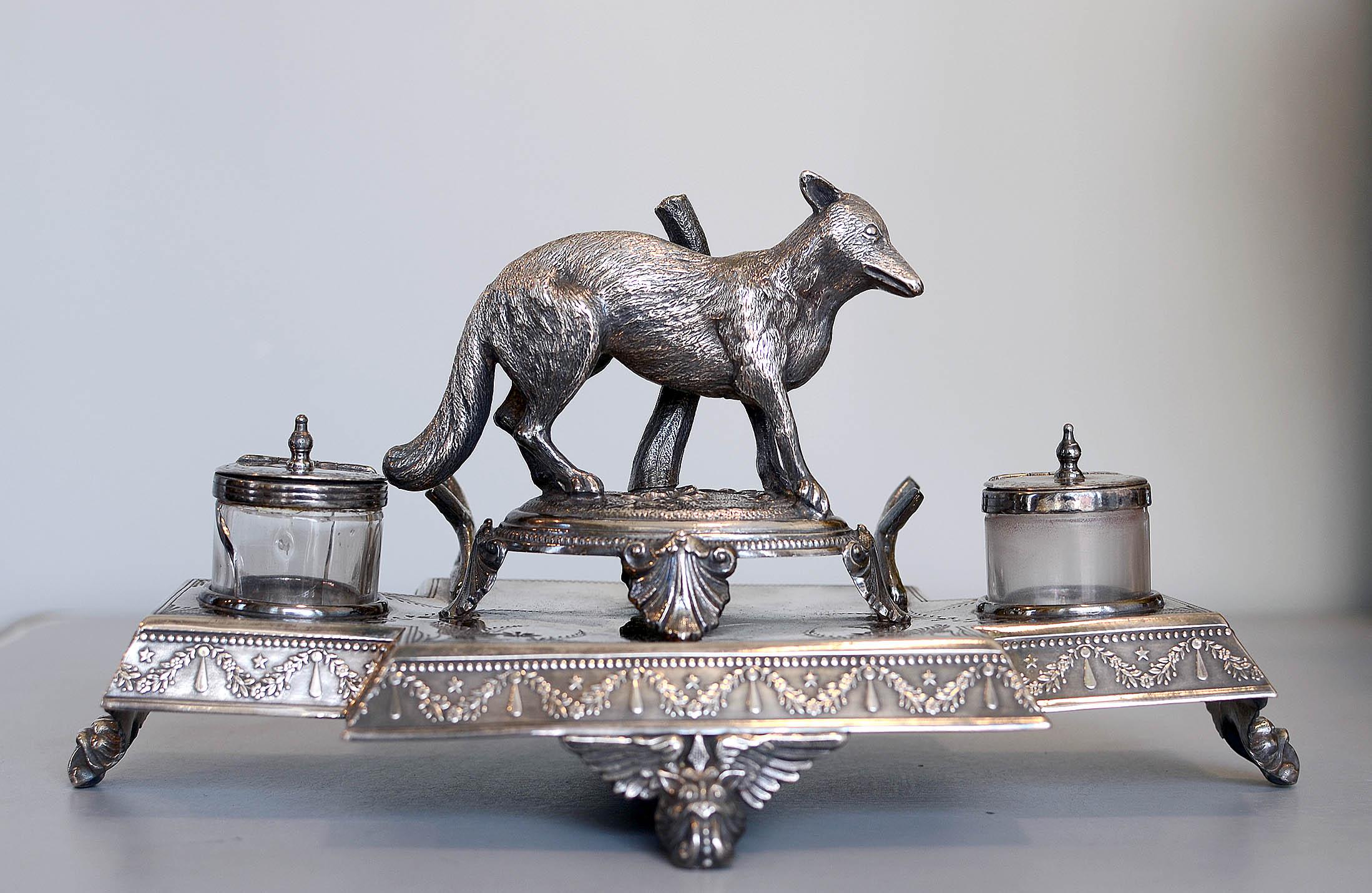 James Deakin & Sons Ltd.
Sheffield, England; ca. 1897-1935
Silver plated copper and glass

Approximate size: 11 (w) x 6 (h) x 6 (d) in.

This lovely silver-plated inkwell features an elegant base with a swag and teardrop raised motif along its