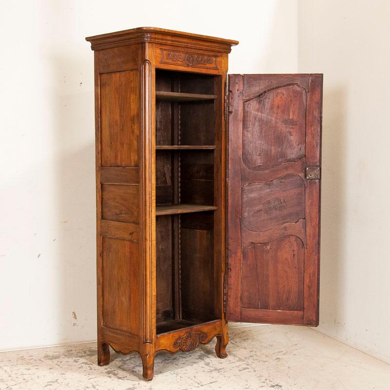The beautiful walnut wood glows with life in this single door armoire from France. The 3 carved panels in the front door are echoed on each side. Carving along the upper and lower front center add a romantic touch. Note the attractive hardware,