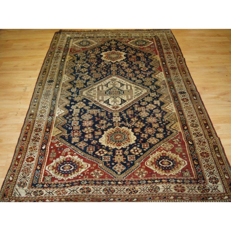 A good Antique single medallion Qashqai rug, with tribal design and faded colour.

The rug has a large central medallions containing the traditional Qashqai design along with other tribal elements, the indigo blue field is filled with tribal