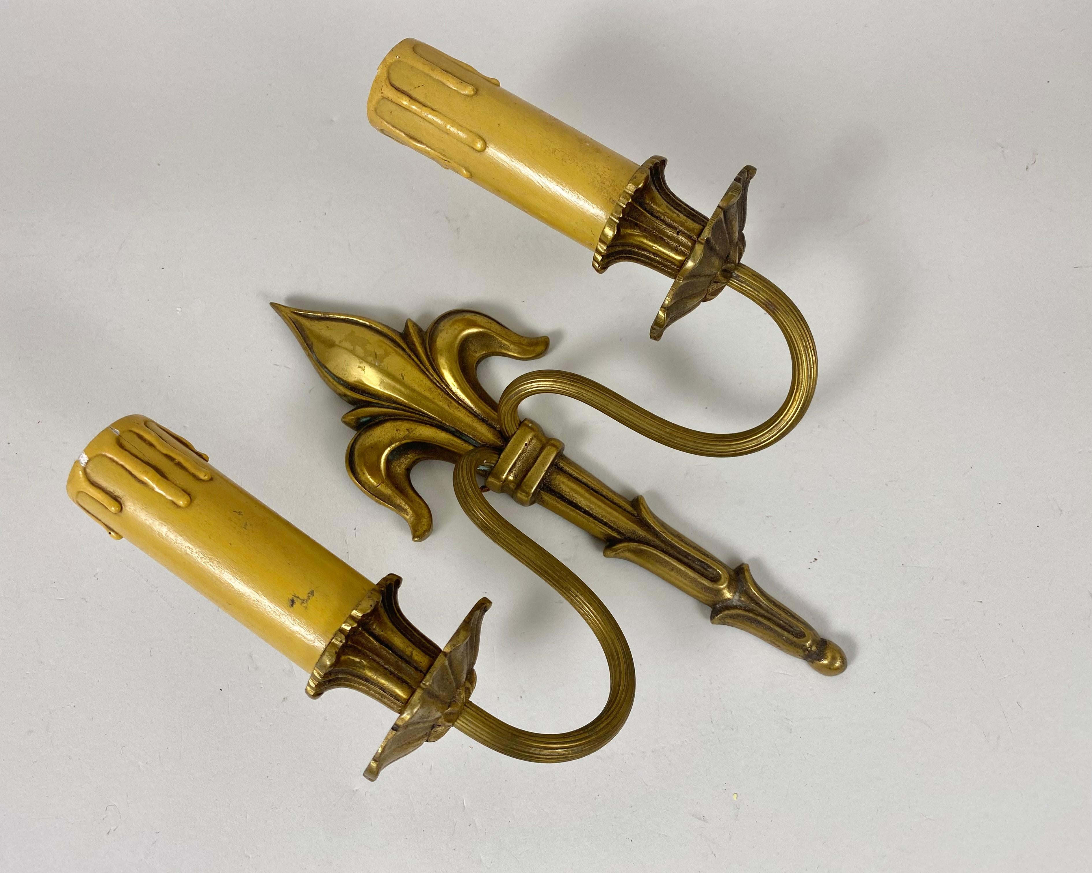 A single bronze sconce with stunning hand-made decor. Ornate fleur-de-lis (lily flower) motif detailing on top. Floral motif details on candle holder part.

Manufactured in France, circa 1930s.

This wall lamp will perfectly fit into your interior,