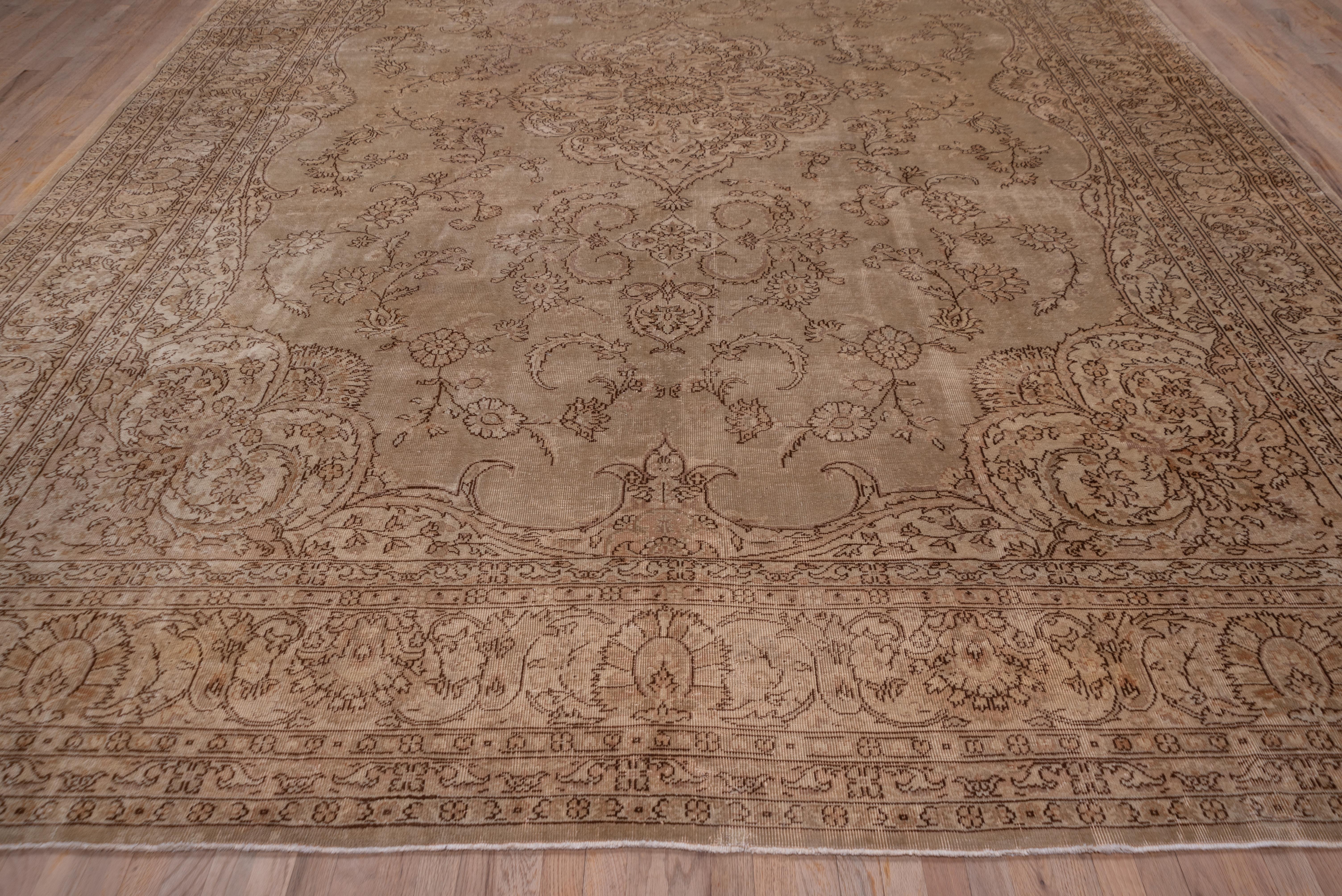 This east Turkish workshop carpet has a brown outlined pattern in the tan field of a pendant medallion and palmette arabesques and very split leaf corners. The beige border displays two palmette types and fat acanthus leaves.