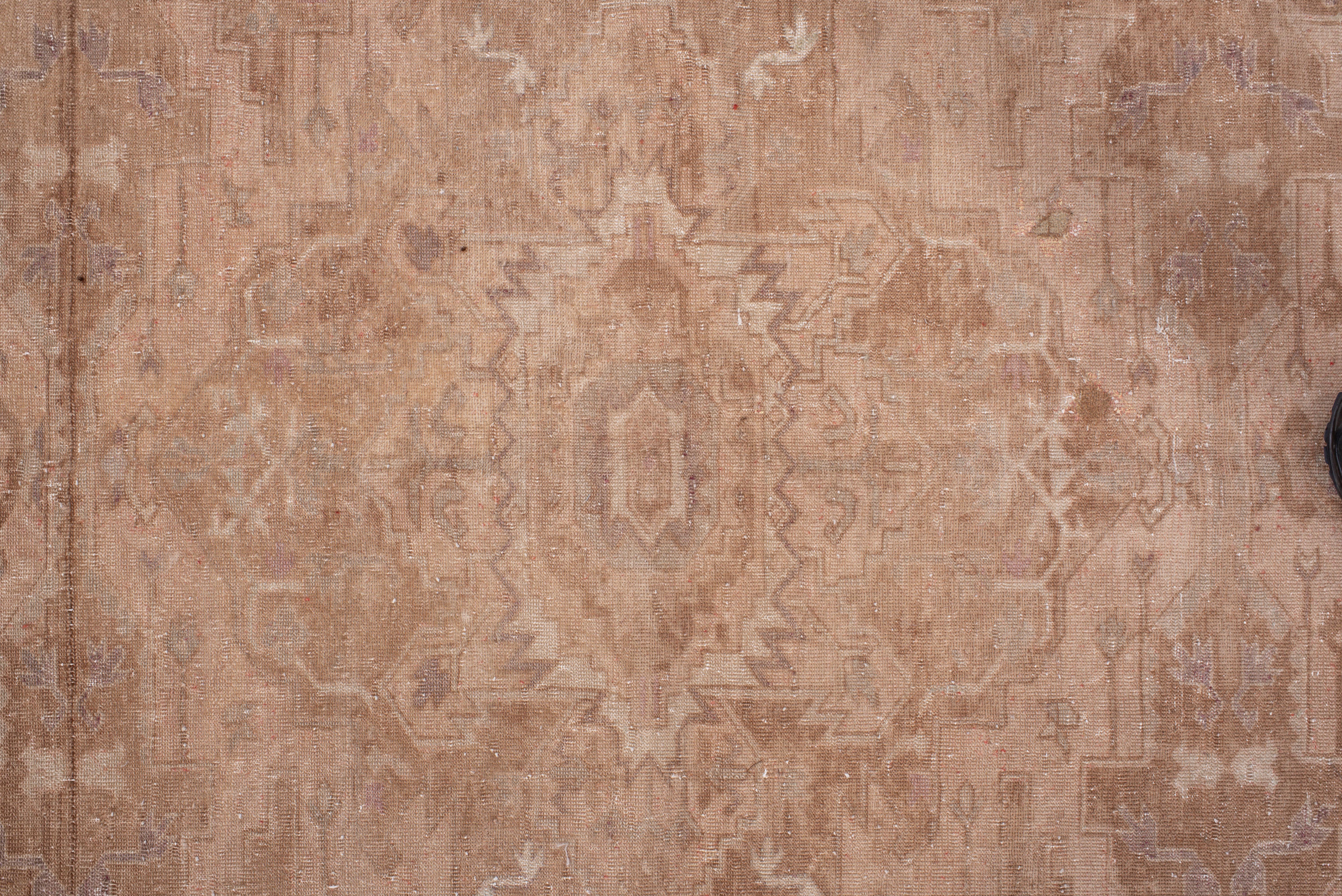 This antique Sivas rug offers a refined tonal palette of warm blush, dusty rose, and soft beige, woven into a symmetrical medallion layout that subtly emerges from the field. The faded hues and delicate detailing speak to decades of graceful wear,