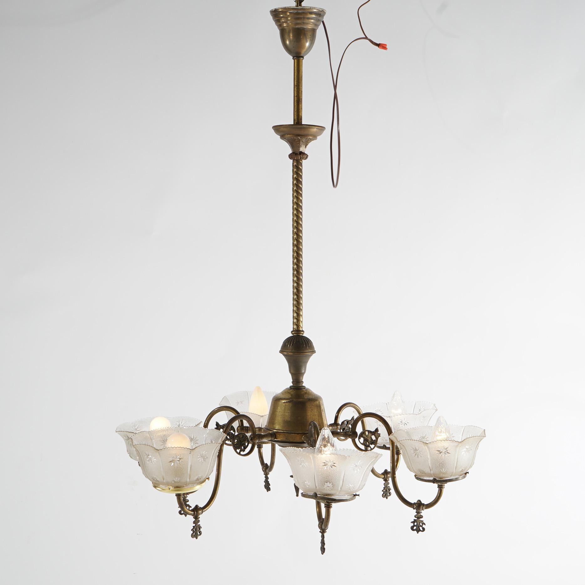 An antique electrified gas chandelier offers brass construction with six scroll form arms terminating in lights with glass shades, c1890

Measures - 41