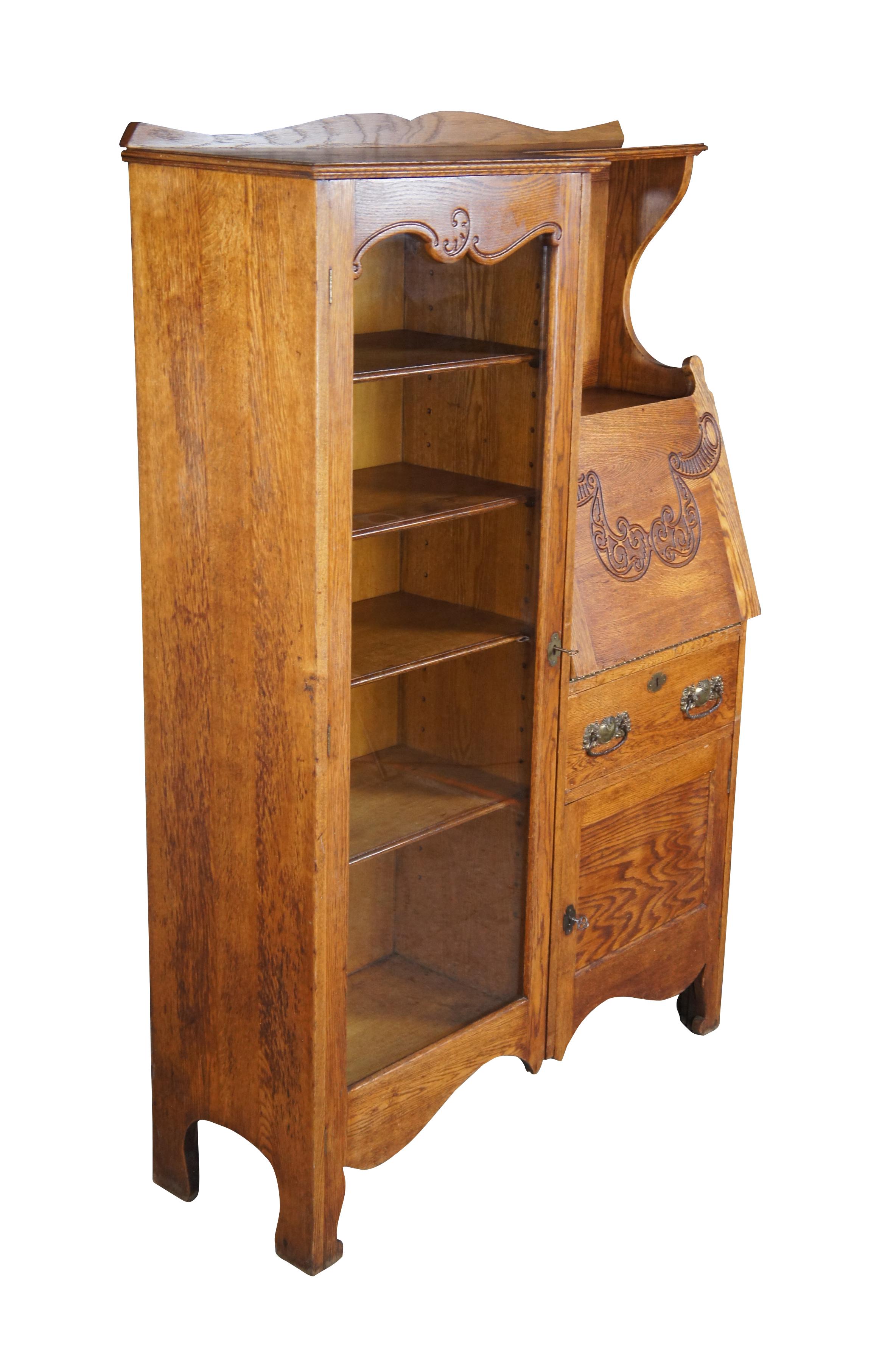 Antique Late Victorian side by side secretary desk and curio bookcase by Skandia Furniture Company, circa 1900s. Made of oak featuring a serpentine backsplash over a glass front bookcase and drop front secretary with carved details below mirror. 