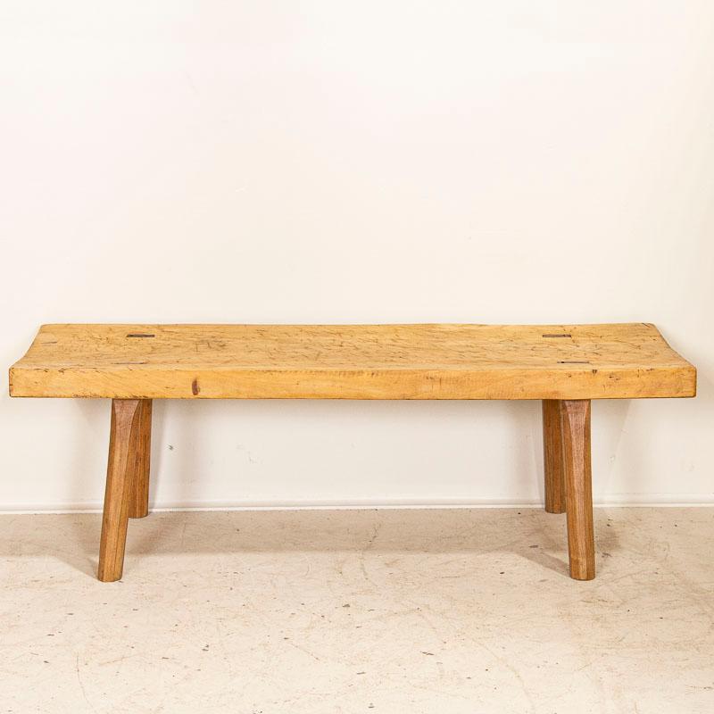 The thick slab top draws one to this rustic coffee table due to the heavy distress seen in every scratch, crack and deep gouges that came from years of constant use (likely in a butcher's shop). Even the old, dried out worm holes and hand carved
