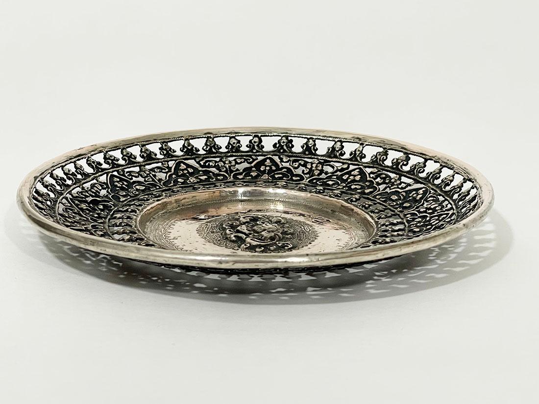 Antico piatto decorativo Yogya traforato di piccole dimensioni

Un antico piatto indonesiano Yogya, riccamente decorato. Il bordo esterno è circondato da tre anelli traforati con scene di foglie. Al centro un motivo floreale decorato a rilievo con