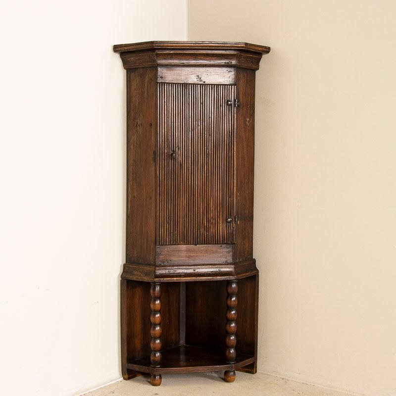 It is the attractive, simple carved details along the front panel that captures the eye in this delightful small corner cabinet from the Swedish countryside. The canted sides and turned, rounded legs resting on a lower shelf add to the visual