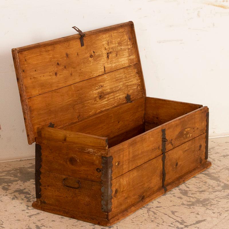 There is something inviting in this simple, narrow box or small trunk. Perhaps it is the warm pine that has taken on a deeper patinal with age, or the hand-wrought iron corners and hinges that reveal its age and were used to reinforce it providing