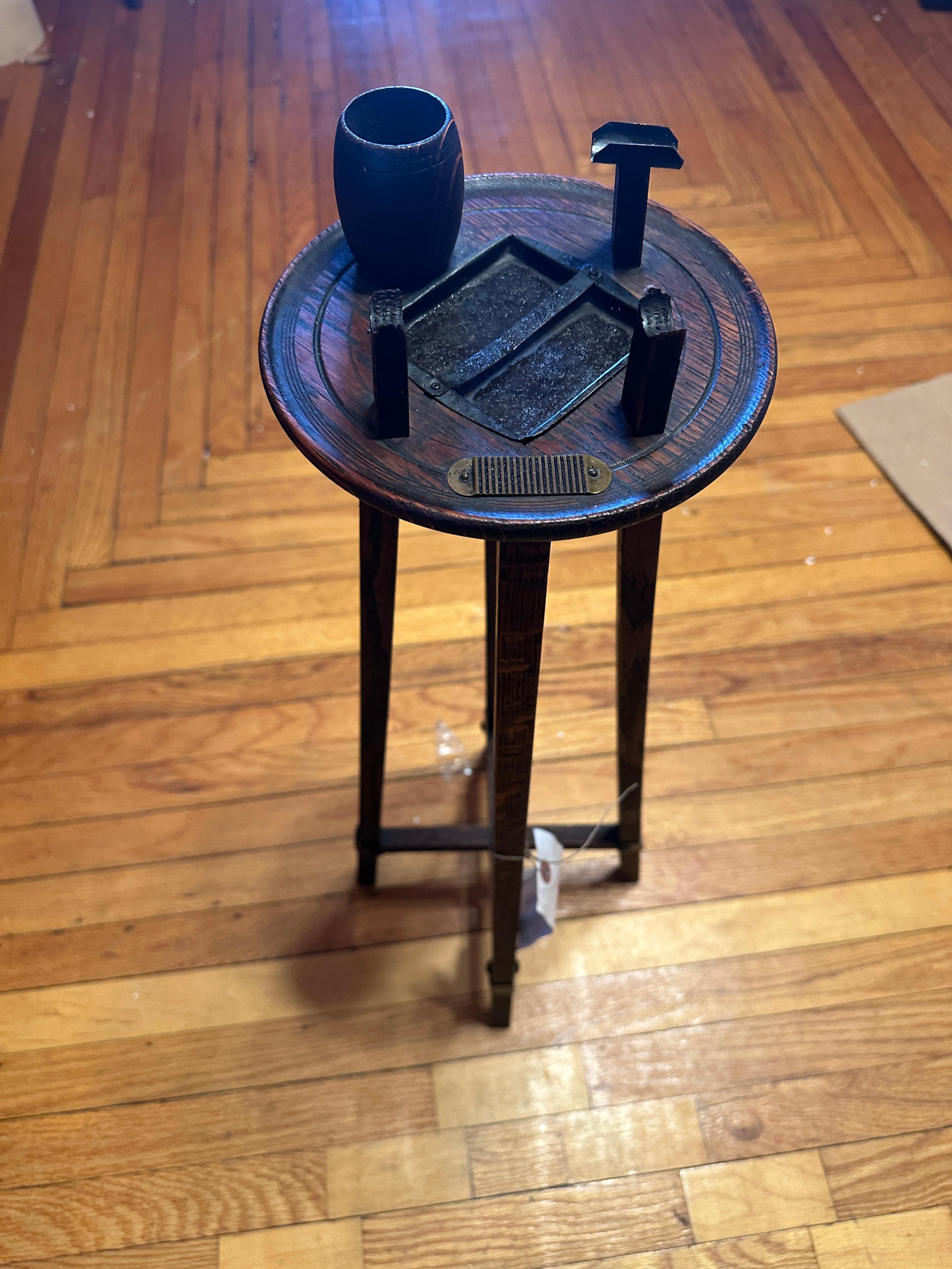 This is a very nice small smoking stand from the Stickley Era (early 1900s).  It is in excellent condition. Besides an ash tray, there is a cup for matches, a match striker, and holders for both a pipe and a cigar.  Measuring 24