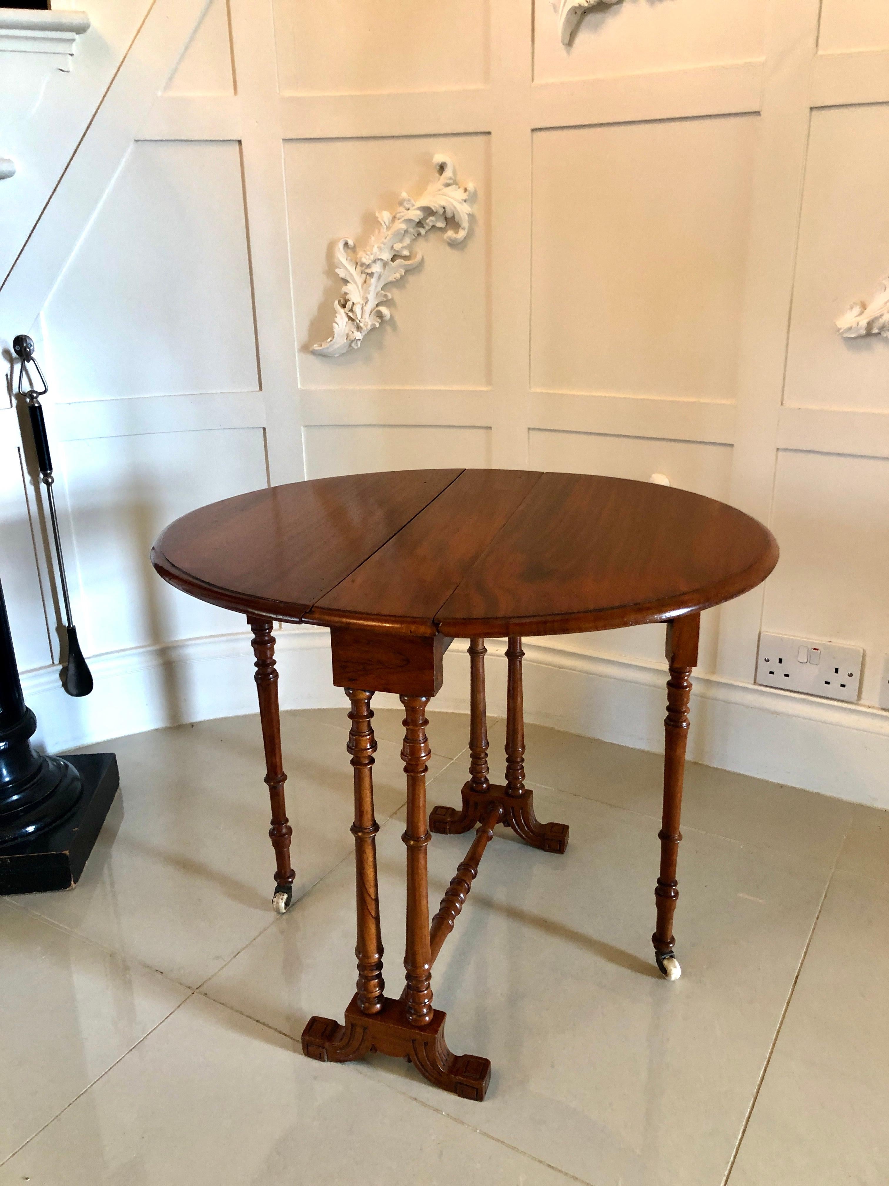 Antique small Victorian walnut drop-leaf Sutherland table having an attractive walnut top with two oval drop leaves. It is raised on four turned walnut columns and two swing out gate legs with original castors. It stands on pretty carved cabriole