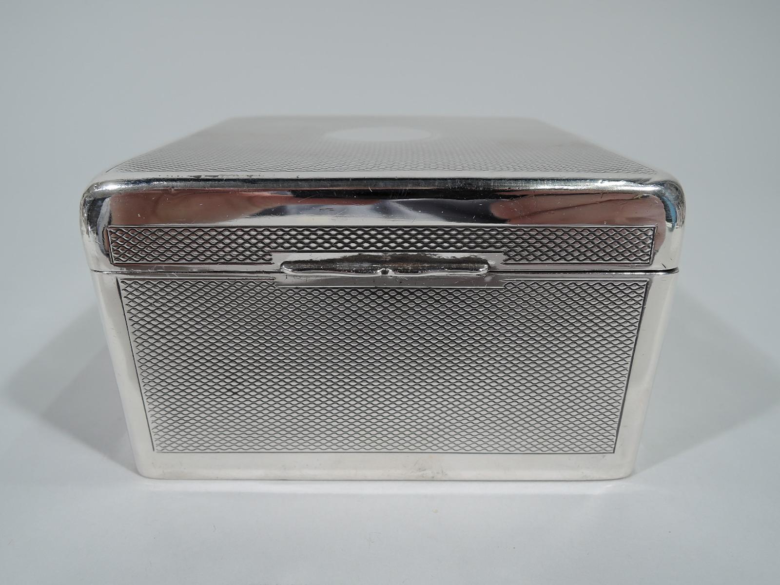 Smart and compact sterling silver box. Made by Arthur & John Zimmerman in Birmingham in 1899. Square with flat and hinged cover. All-over engine-turned ornament in plain frames. Cover has central circular mono plate (vacant) and scrolled tab. Box