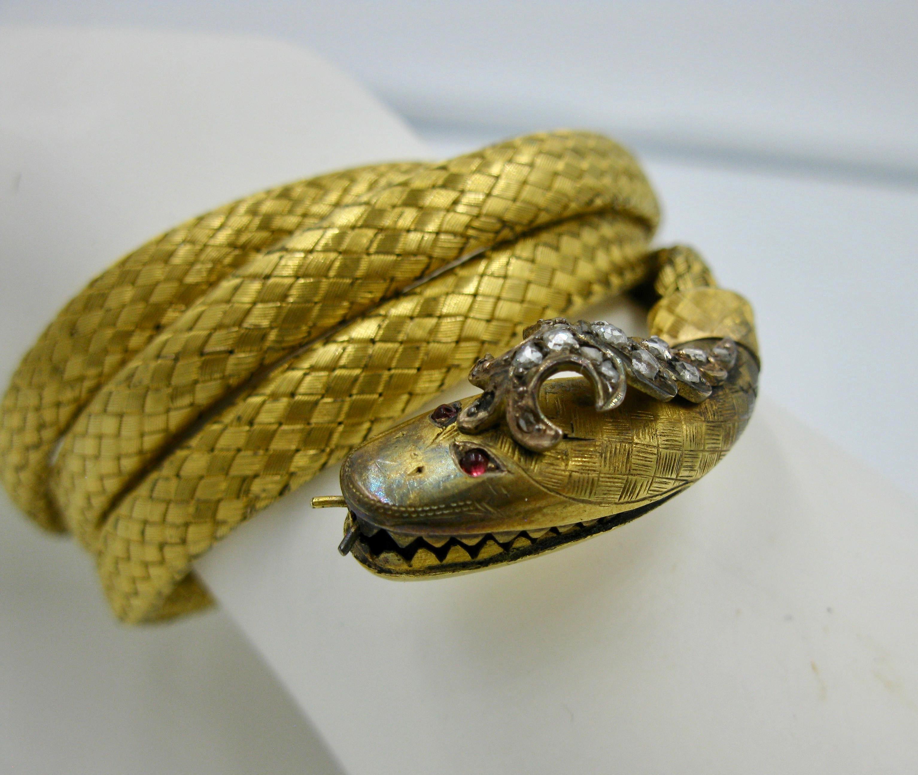 This is a very rare and wonderful antique Victorian Coiled Snake Bracelet in 14 Karat Gold with a Rose Cut Diamond crown and cabochon Ruby Eyes dating to circa 1840.  A wonderful adjustable mesh design in vibrant rich yellow gold.  The dramatic head