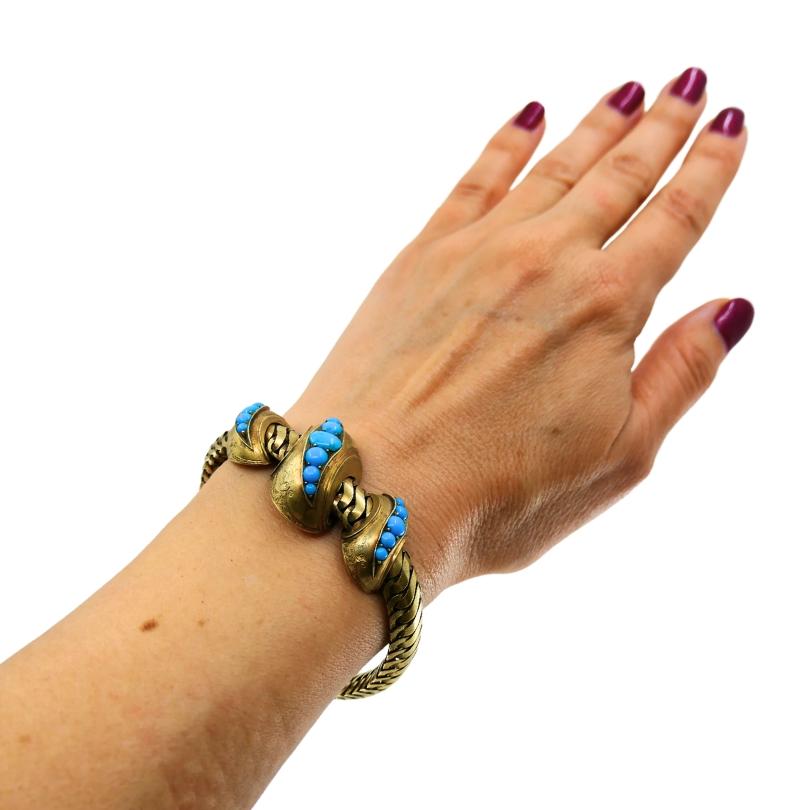 Un magnifique bracelet serpent Antique, en or 10k, avec des turquoises.
La bande du bracelet est composée de maillons d'or tissés de manière complexe, ce qui lui confère une souplesse proche du tissu. Au centre, un motif sculptural en forme de nœud